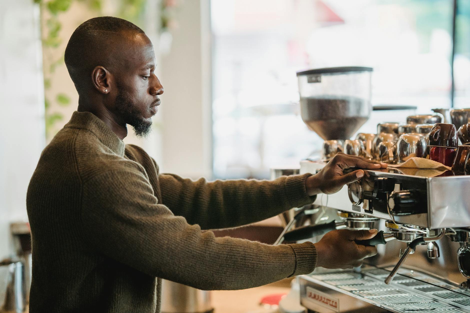 Barista operating automated coffee machine in cafe