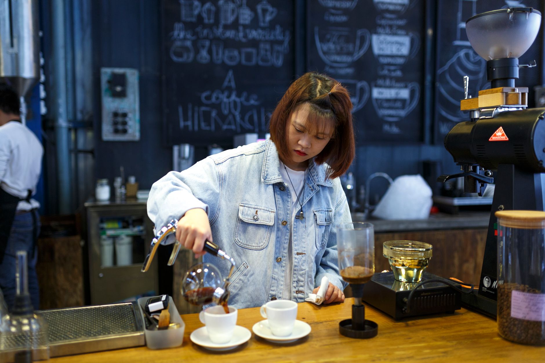 Professional barista operating a commercial-sized French press during morning rush