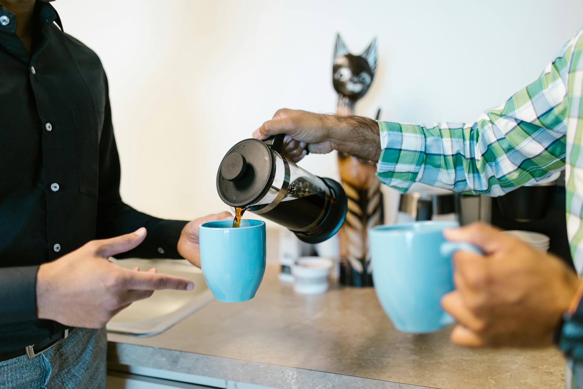 Modern office coffee station with employees pouring drinks