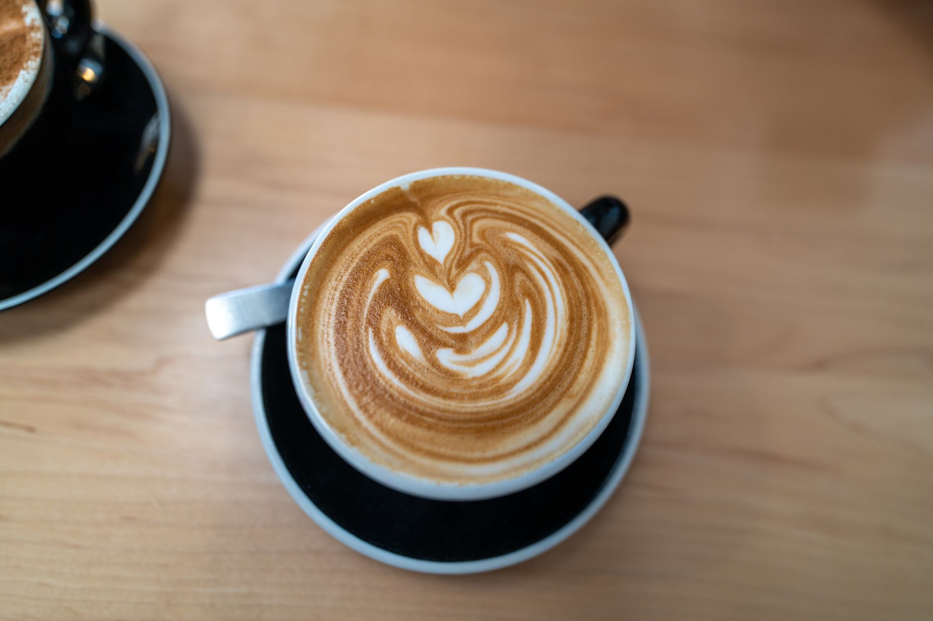 Professional barista creating intricate latte art with etching tools