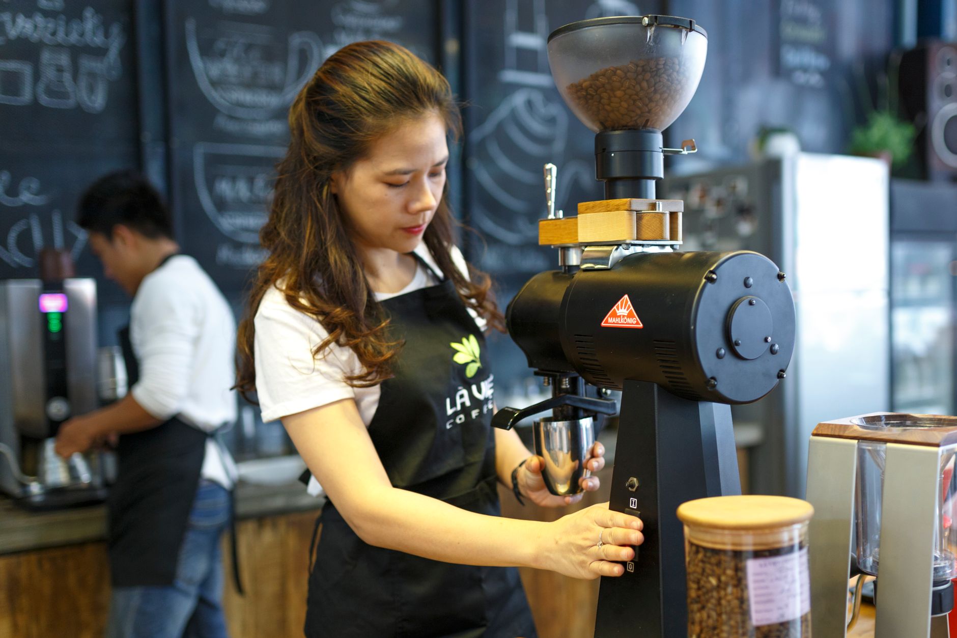 Professional barista preparing espresso drinks in busy Boston cafe