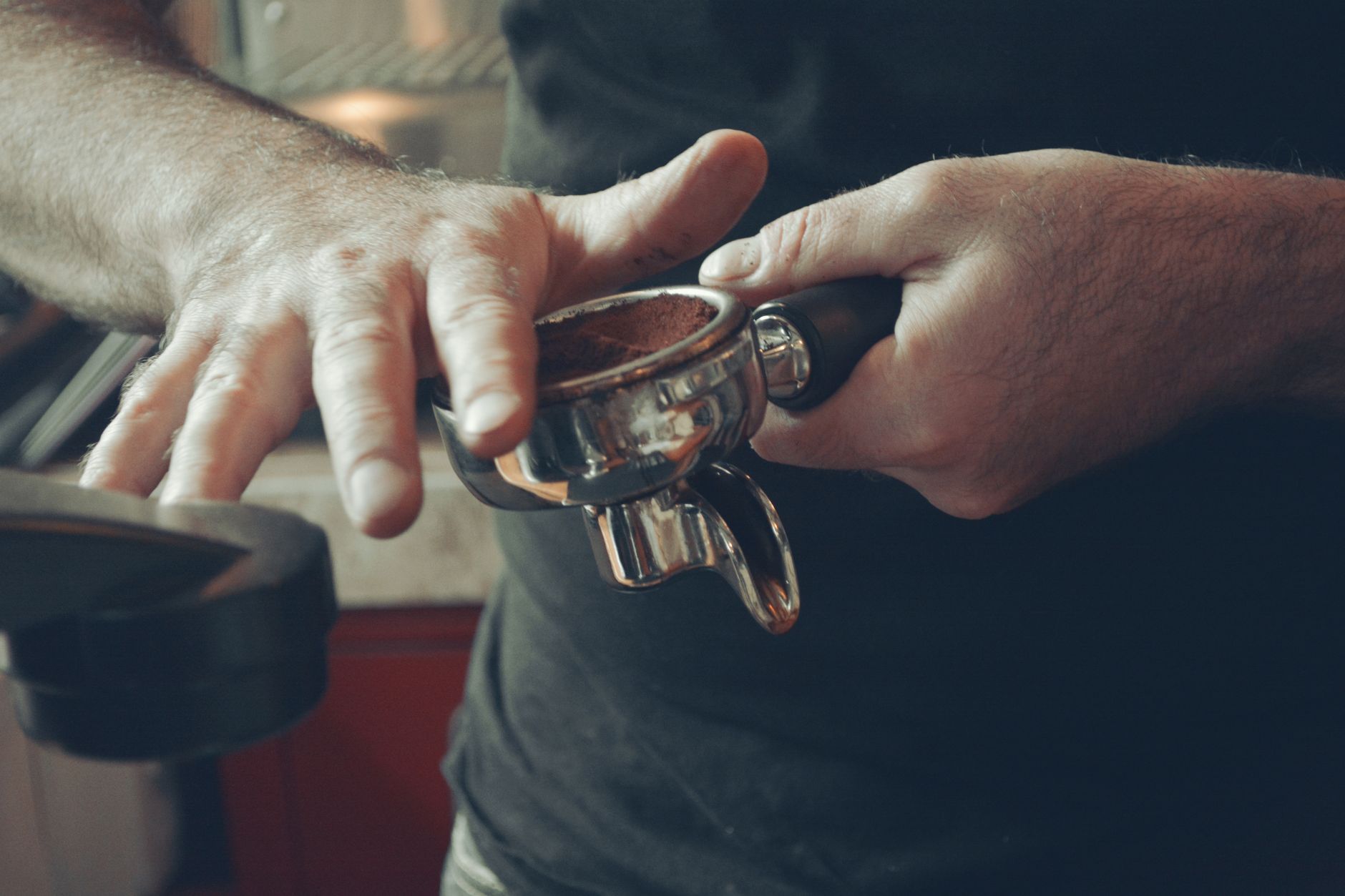 Professional barista rinsing stainless steel coffee filter under running water