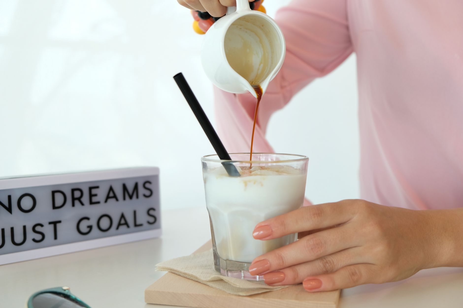 Professional barista pouring latte art using a stainless steel milk pitcher