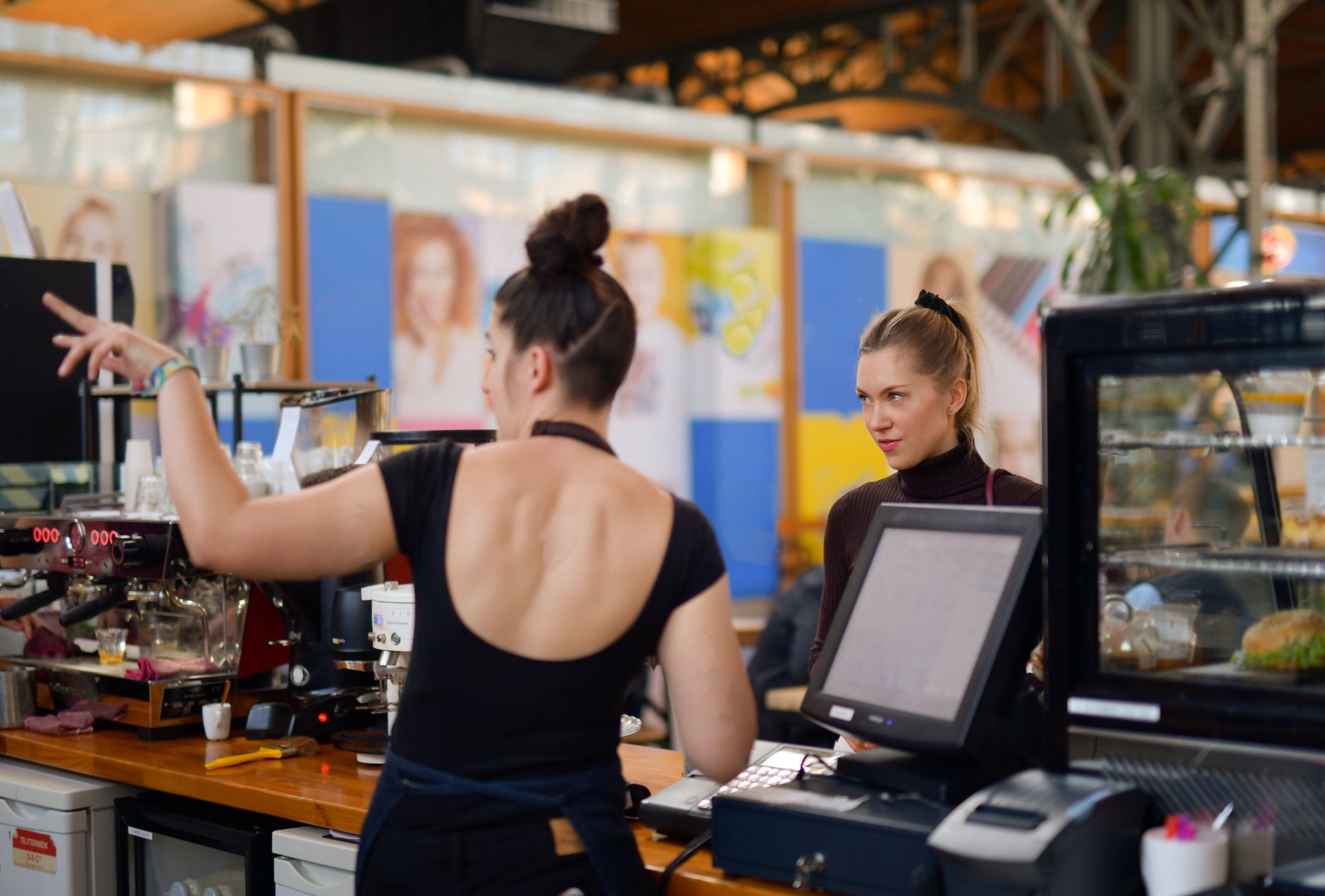 Two women interacting at a café counter, showcasing vibrant atmosphere and customer service.