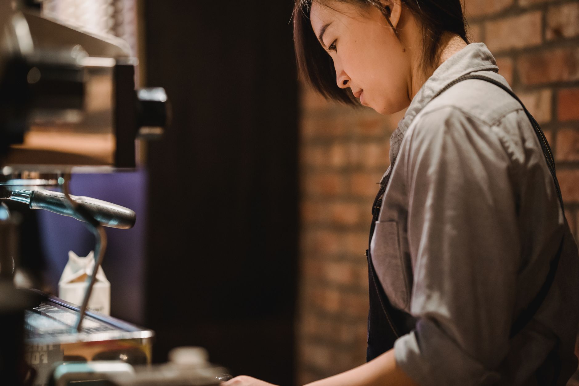 A barista attentively crafting espresso in a cozy café environment with a professional machine.