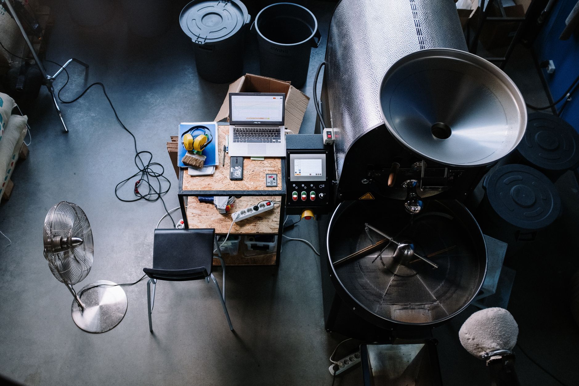 An overhead view of a coffee roastery workspace featuring equipment and a laptop.