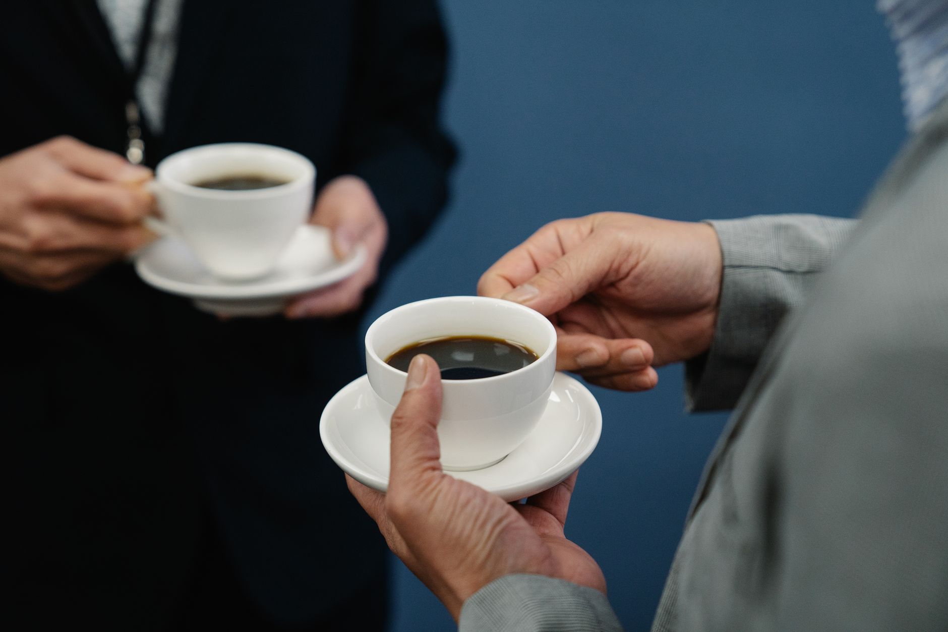 Businessmen in suits holding coffee cups during a casual meeting indoors.