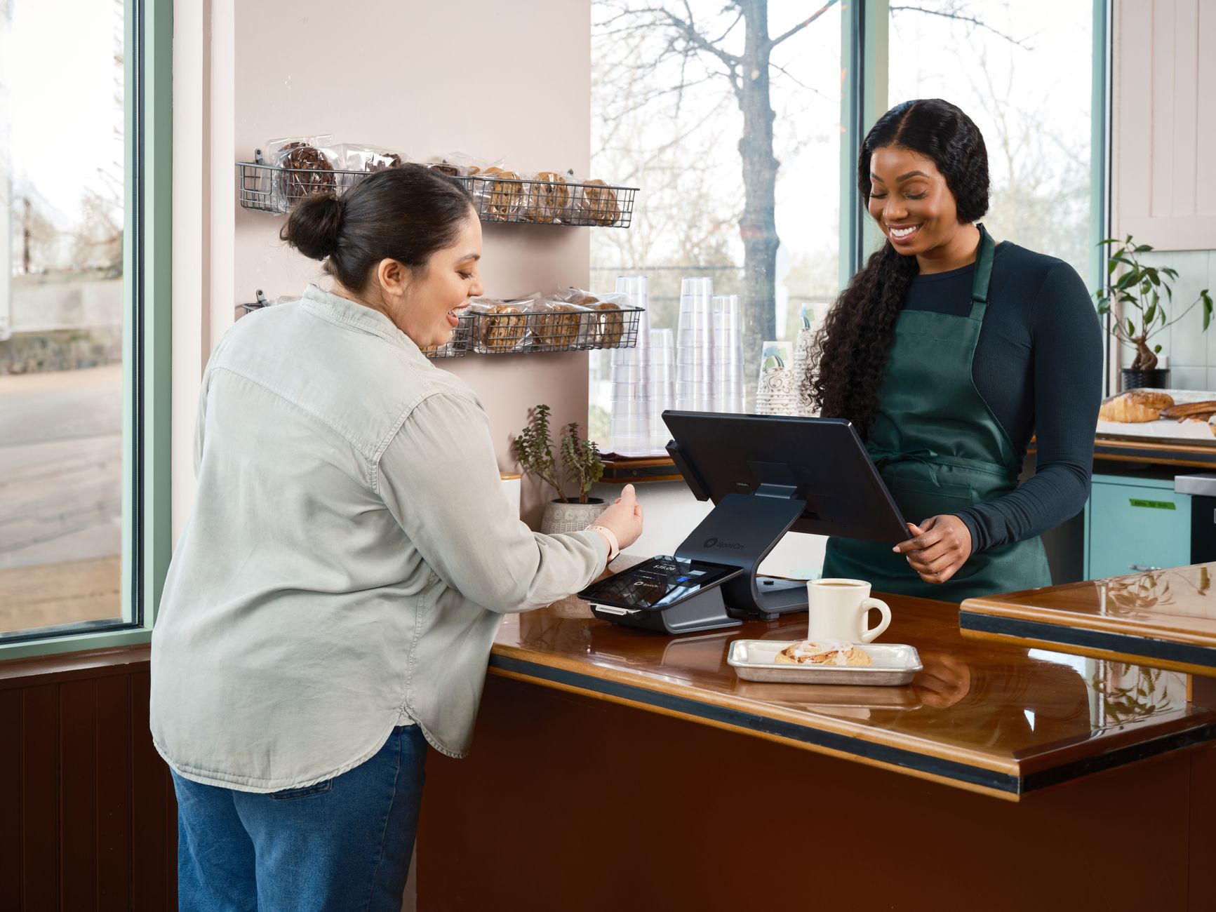 A customer uses contactless payment at a cozy café with a friendly barista.