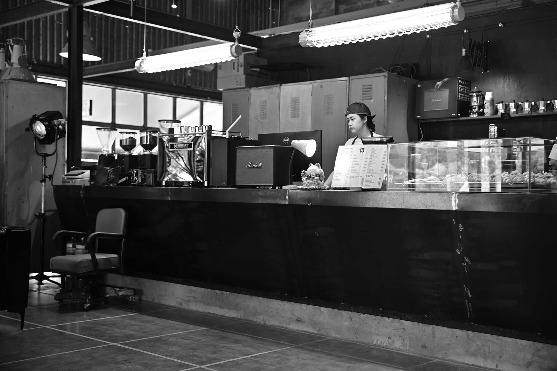 A barista stands behind a cafe counter in a cozy black and white setting.