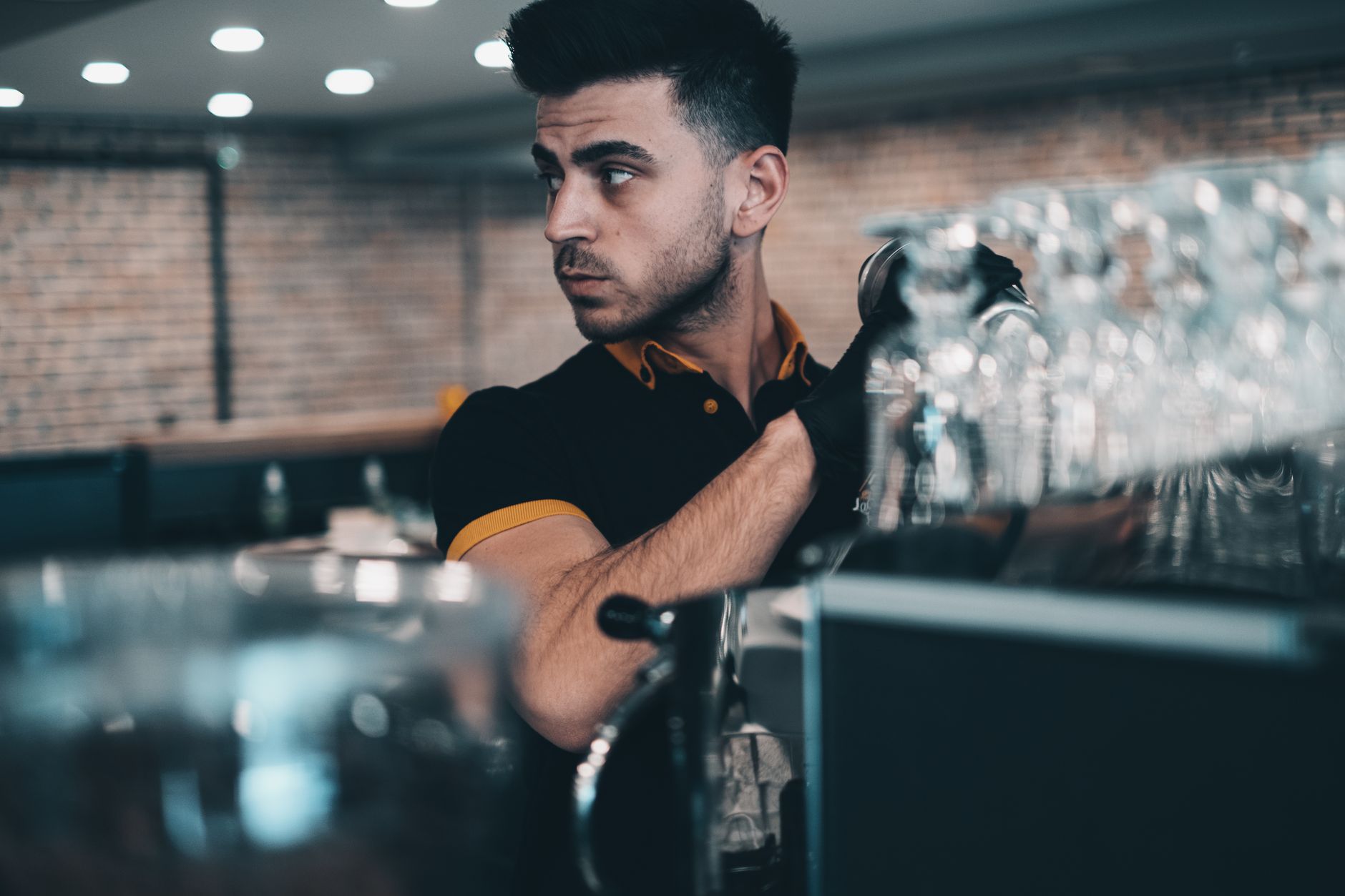 A focused barista prepares coffee behind an espresso machine in an inviting café.