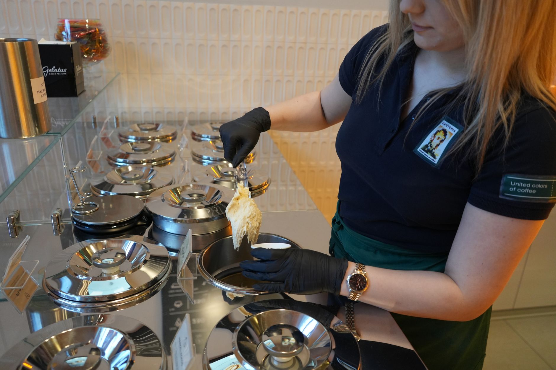 Barista serving gelato at a stylish cafe with a modern interior design.