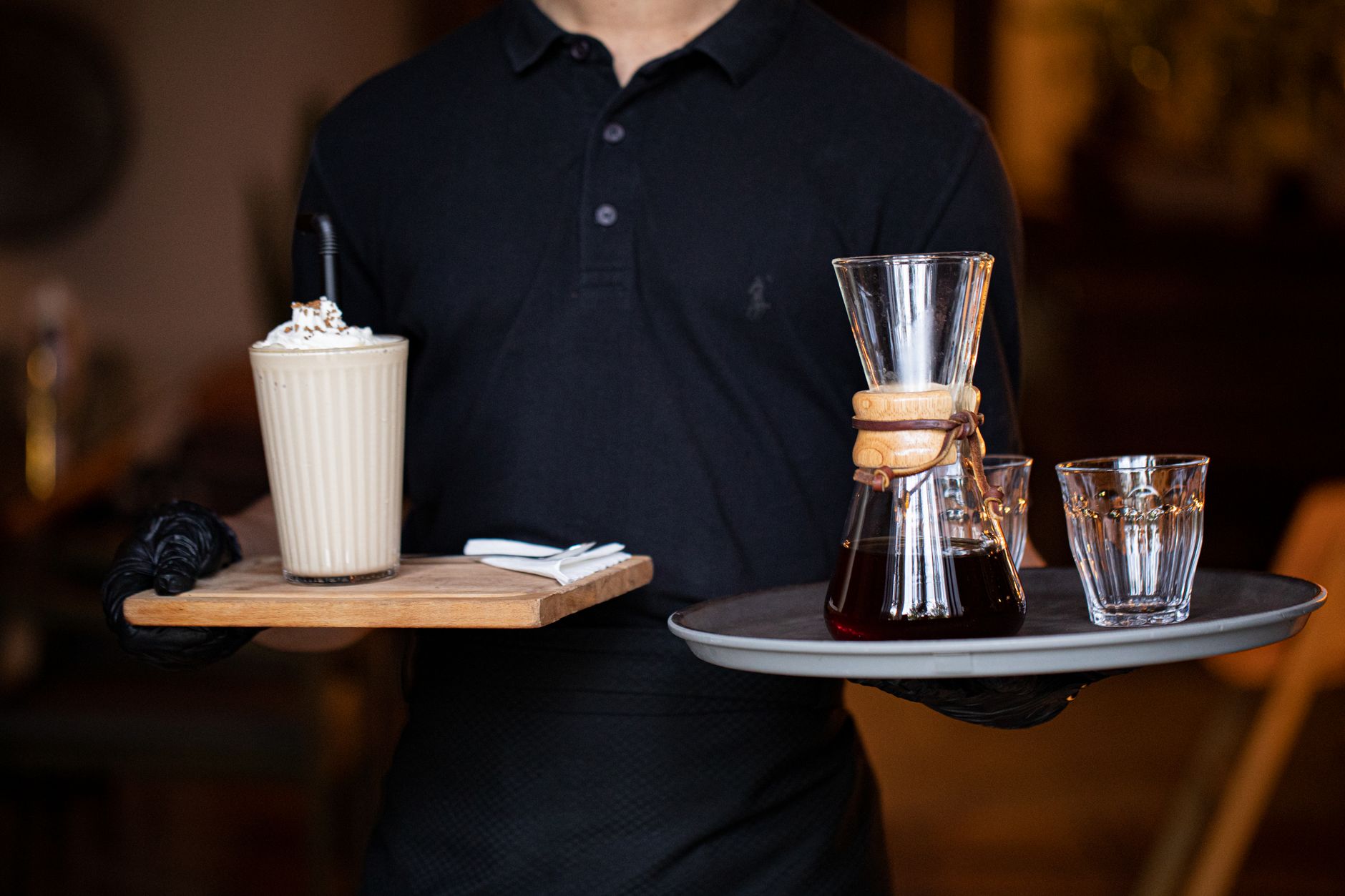 Barista serving a coffee and latte on trays in a cozy café, perfect for beverage promotions.