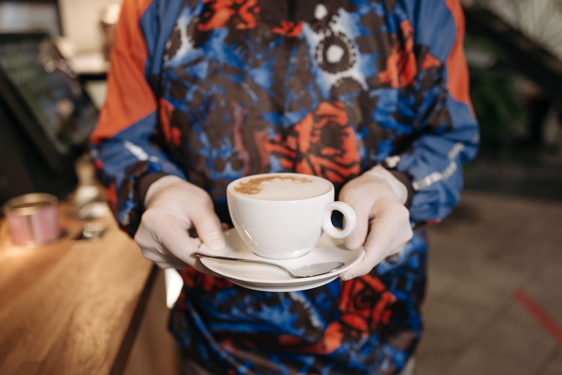 Cozy café setting with a barista serving a hot cappuccino on a saucer.