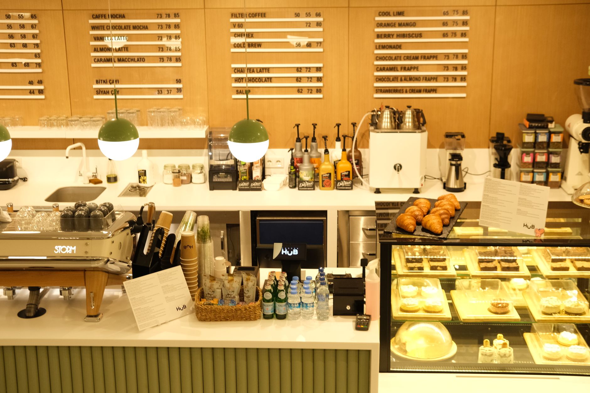 Warm coffee shop interior with menu boards, croissants, and dessert display. Ideal for food and beverage themes.