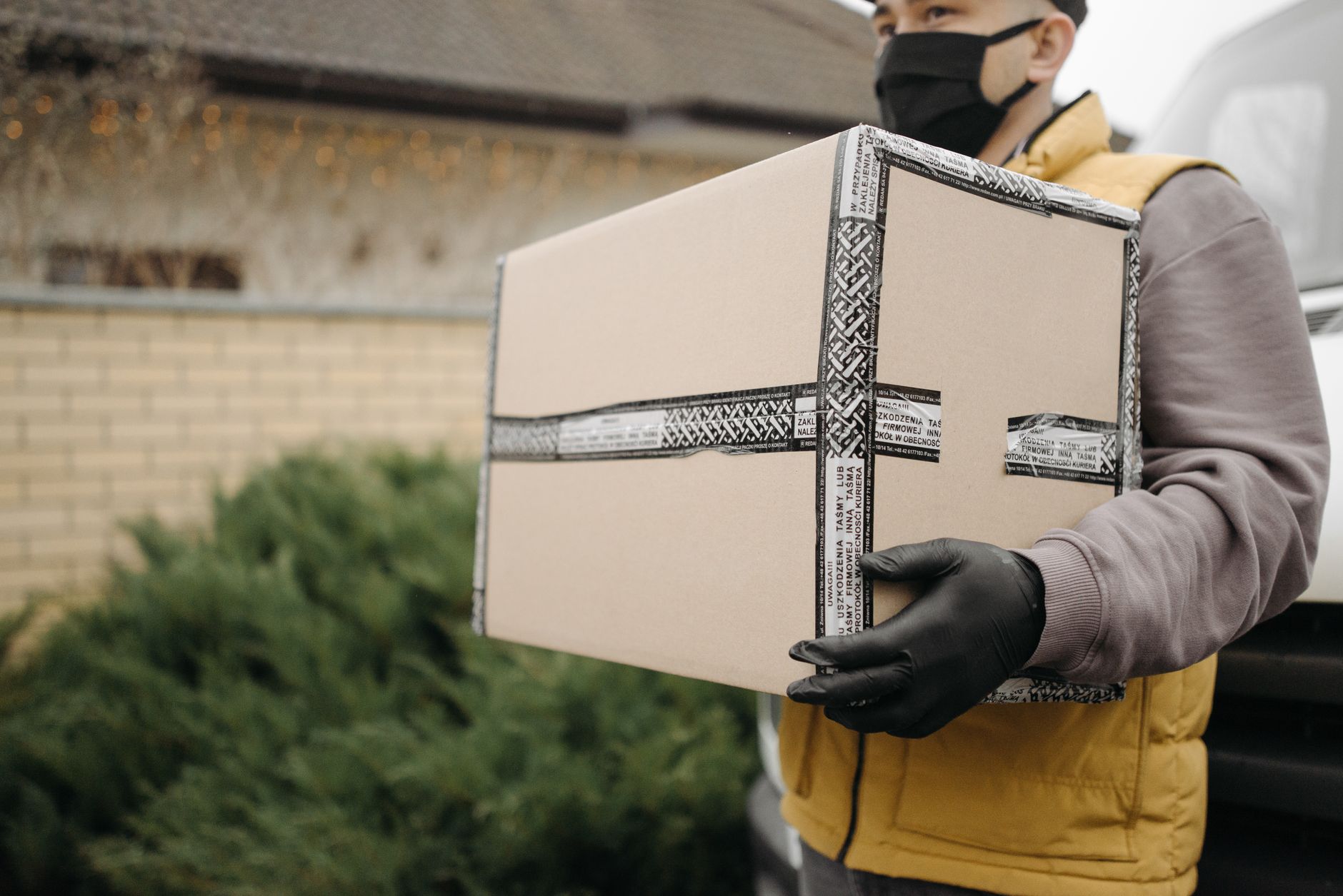 Courier with mask and gloves delivering a package outdoors, embracing the new normal.
