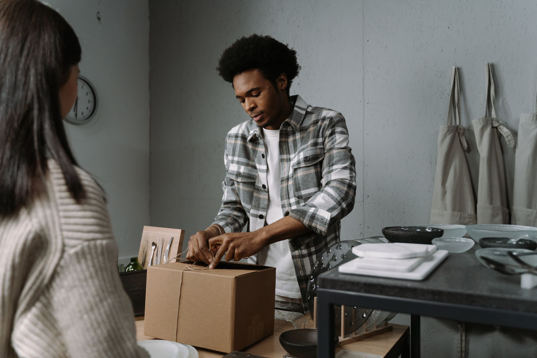 A man carefully packs a box in a retail setting, preparing goods for a customer.