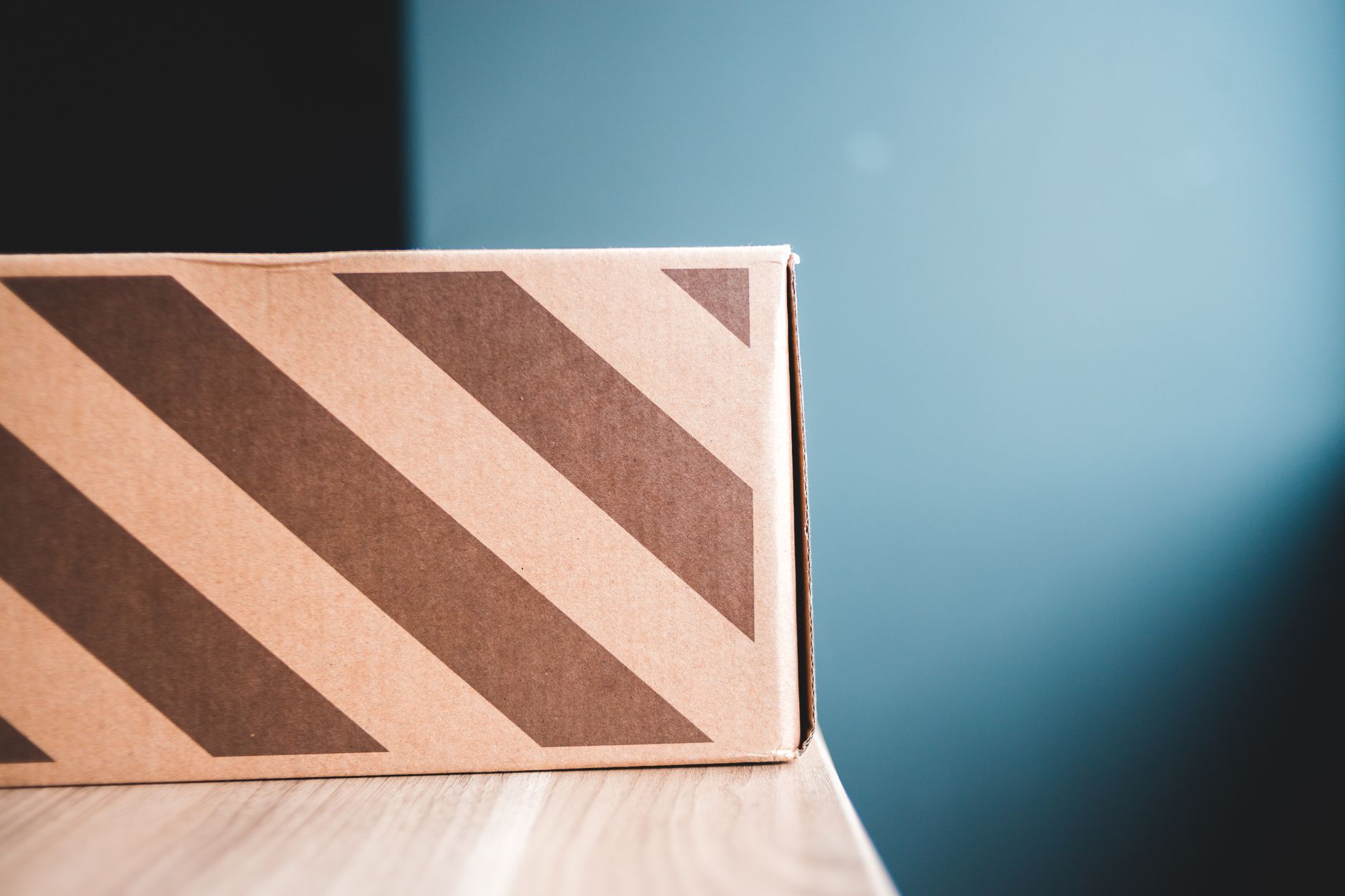 Closeup of carton box with stripes on wooden table against gray wall in apartment