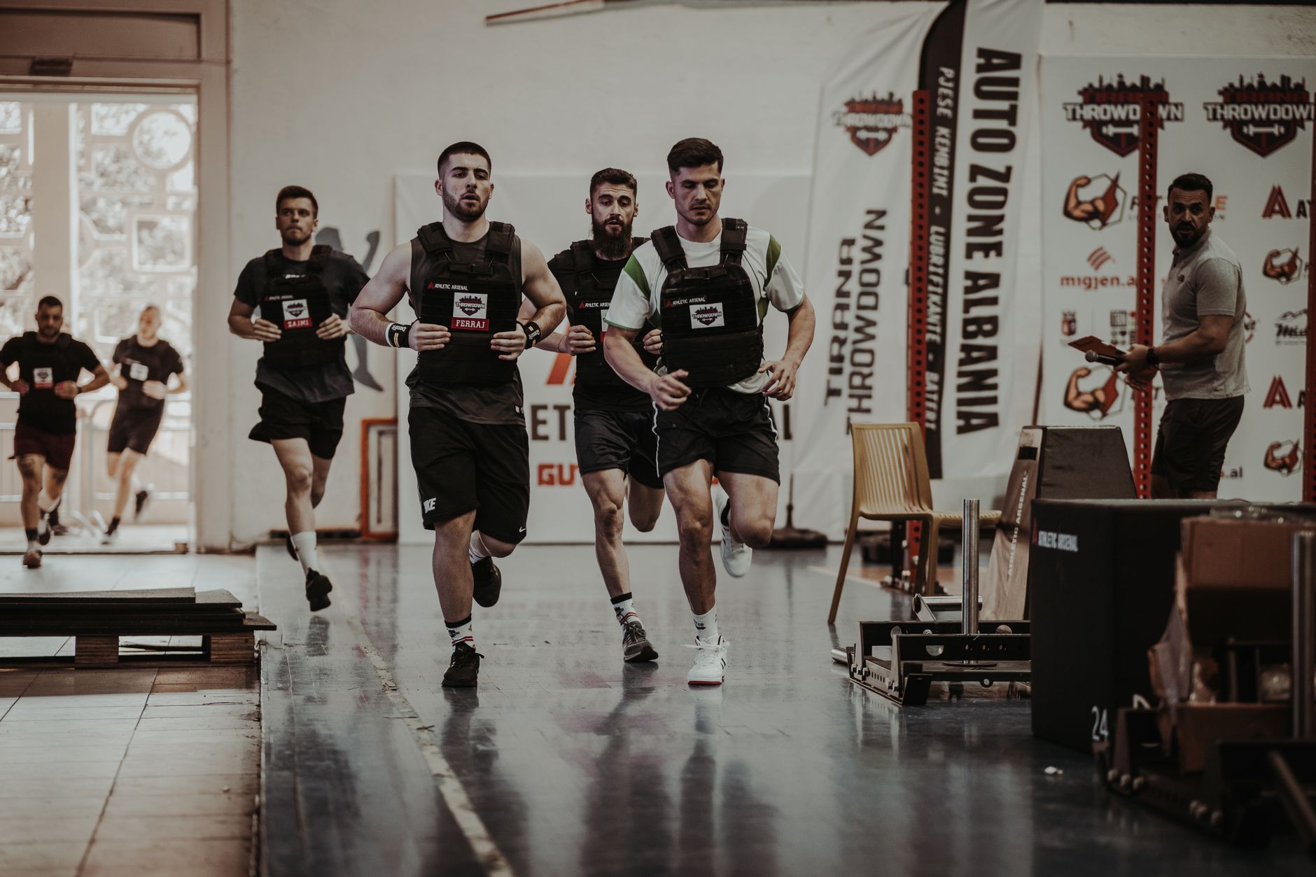 Group of men running in an indoor fitness competition, showcasing athleticism and determination.
