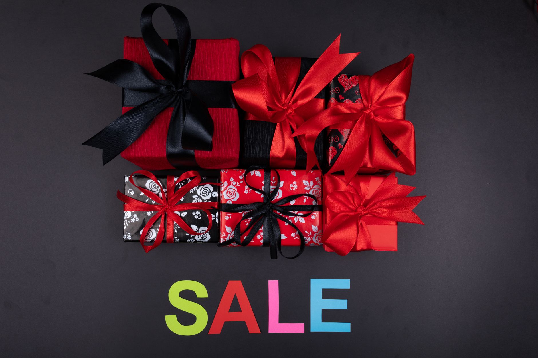 Colorful gift boxes with bows arranged over a SALE sign, perfect for holiday promotions.