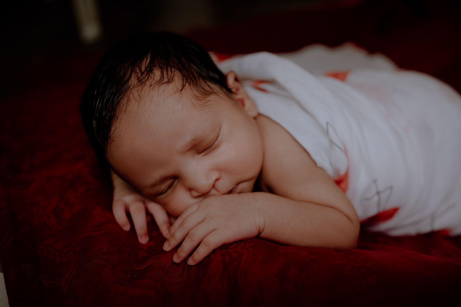 Adorable sleeping baby in a swaddle on a soft red blanket, capturing pure innocence and peace.
