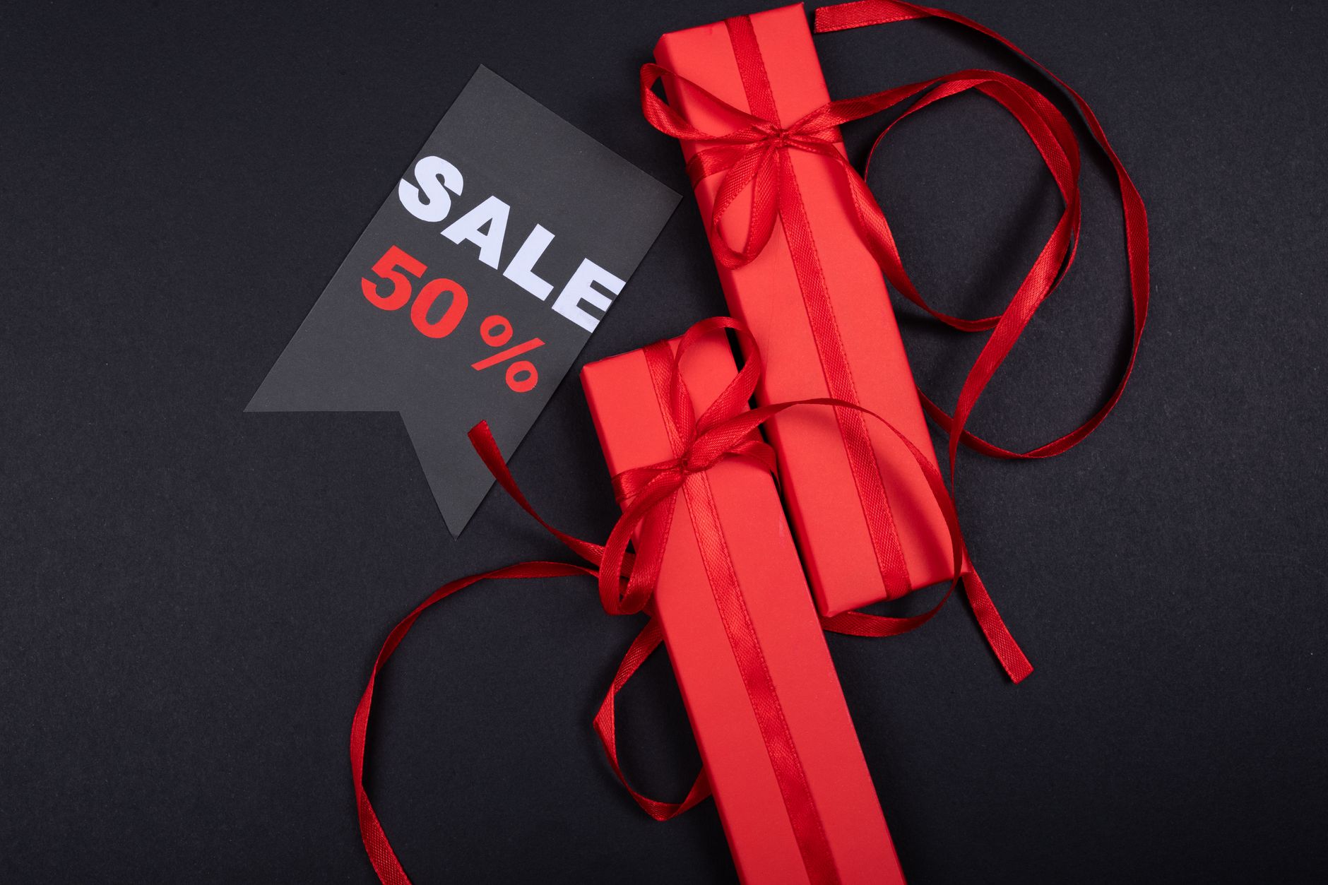 Red gift boxes with ribbons and a prominent 50% sale sign on black background.