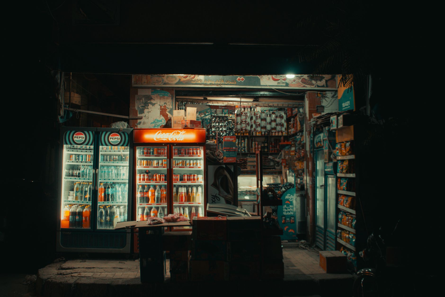 A cozy convenience store in Damanhour, Egypt, with illuminated coolers at night.