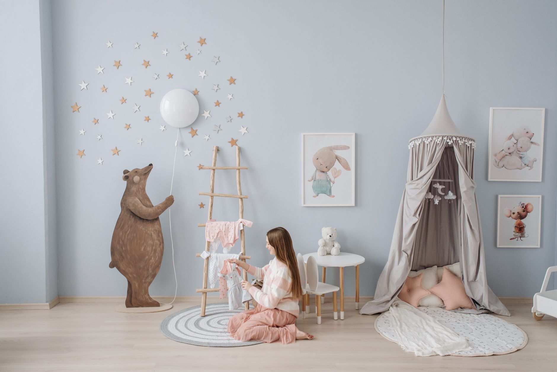 Woman arranging baby clothes in a beautifully decorated nursery with playful decor.