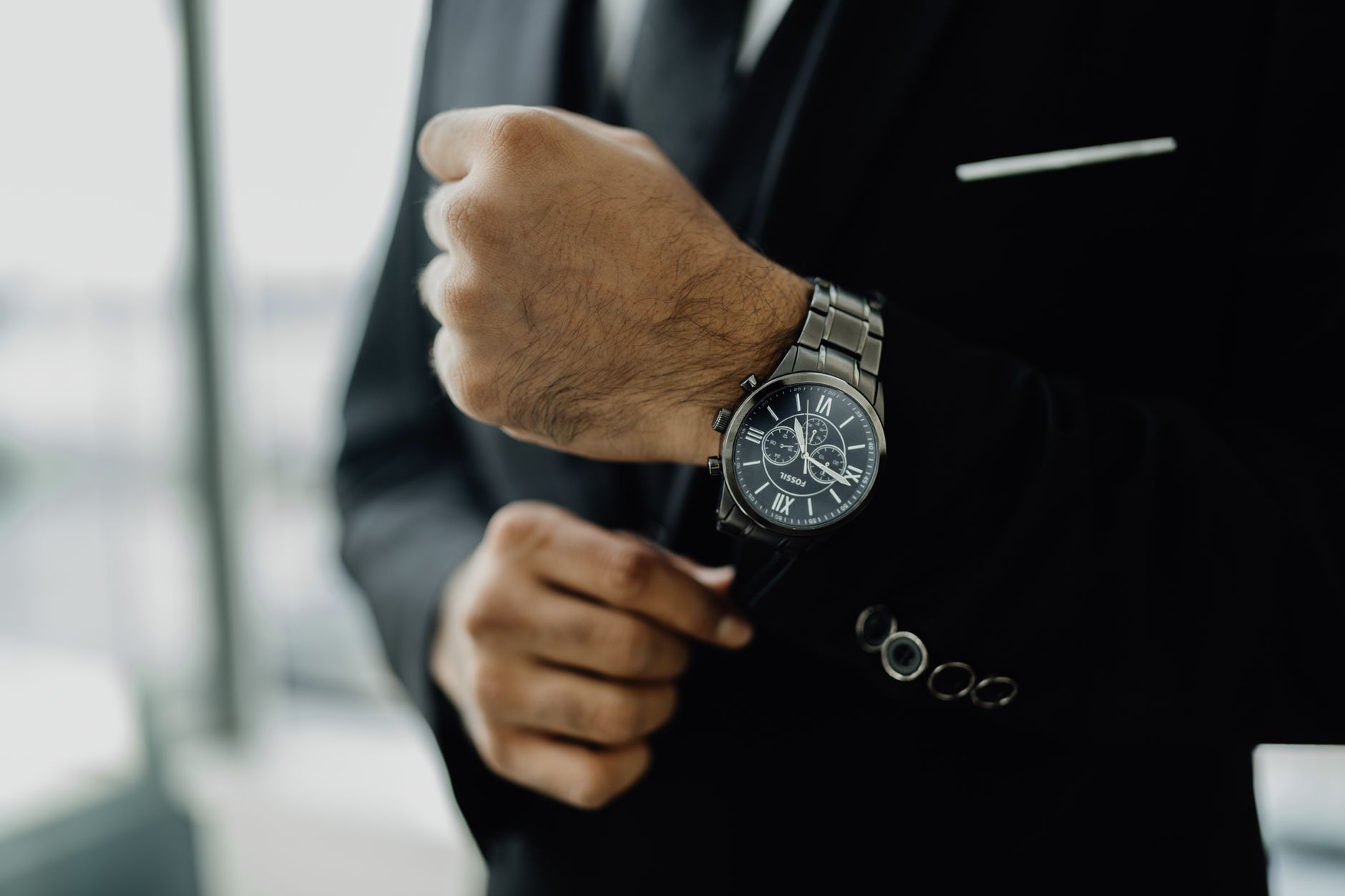 Close-up of a businessman adjusting his elegant wristwatch, showcasing luxury and style.