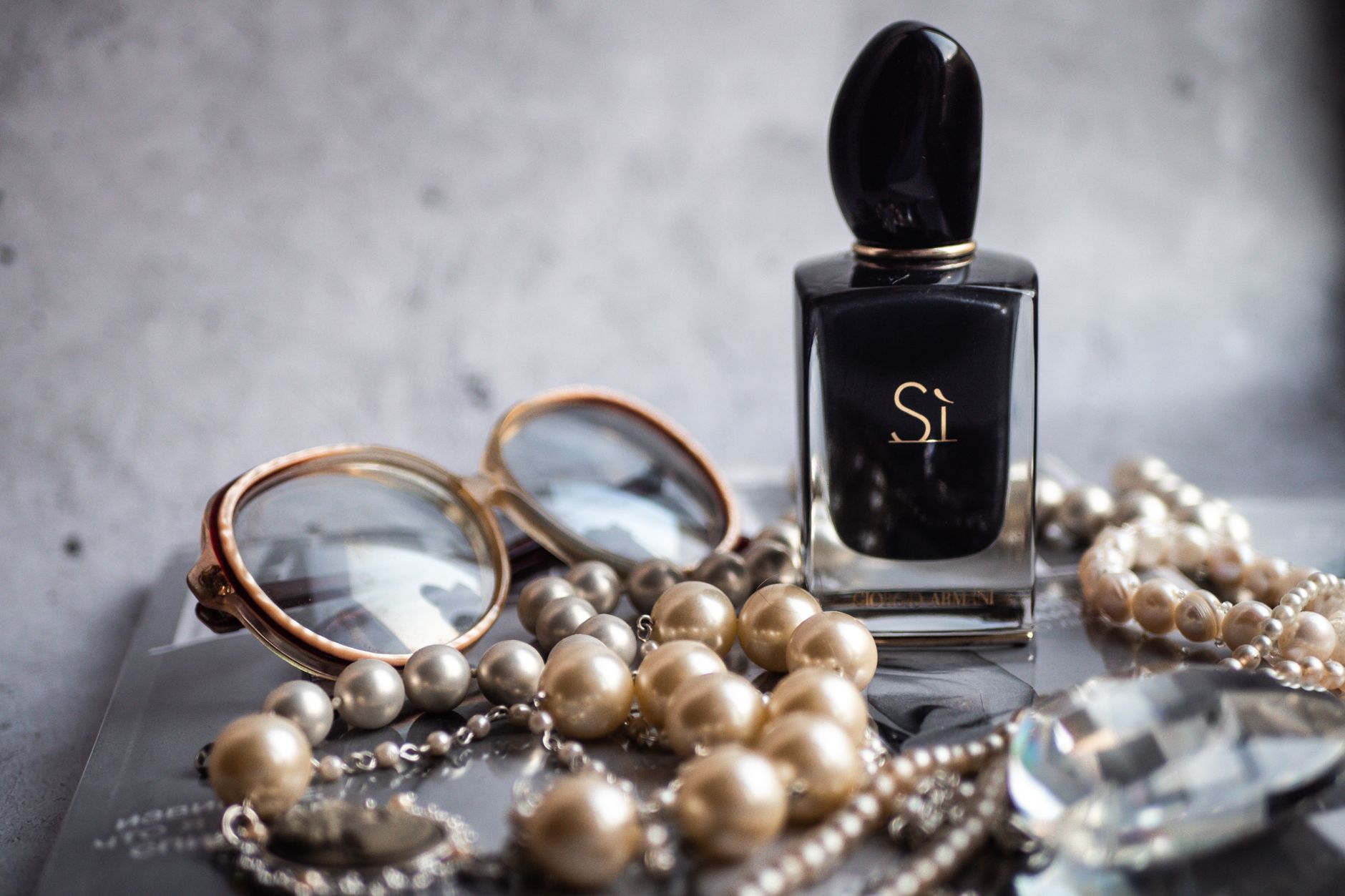 A luxury still life featuring perfume, sunglasses, and pearls for an elegant touch.