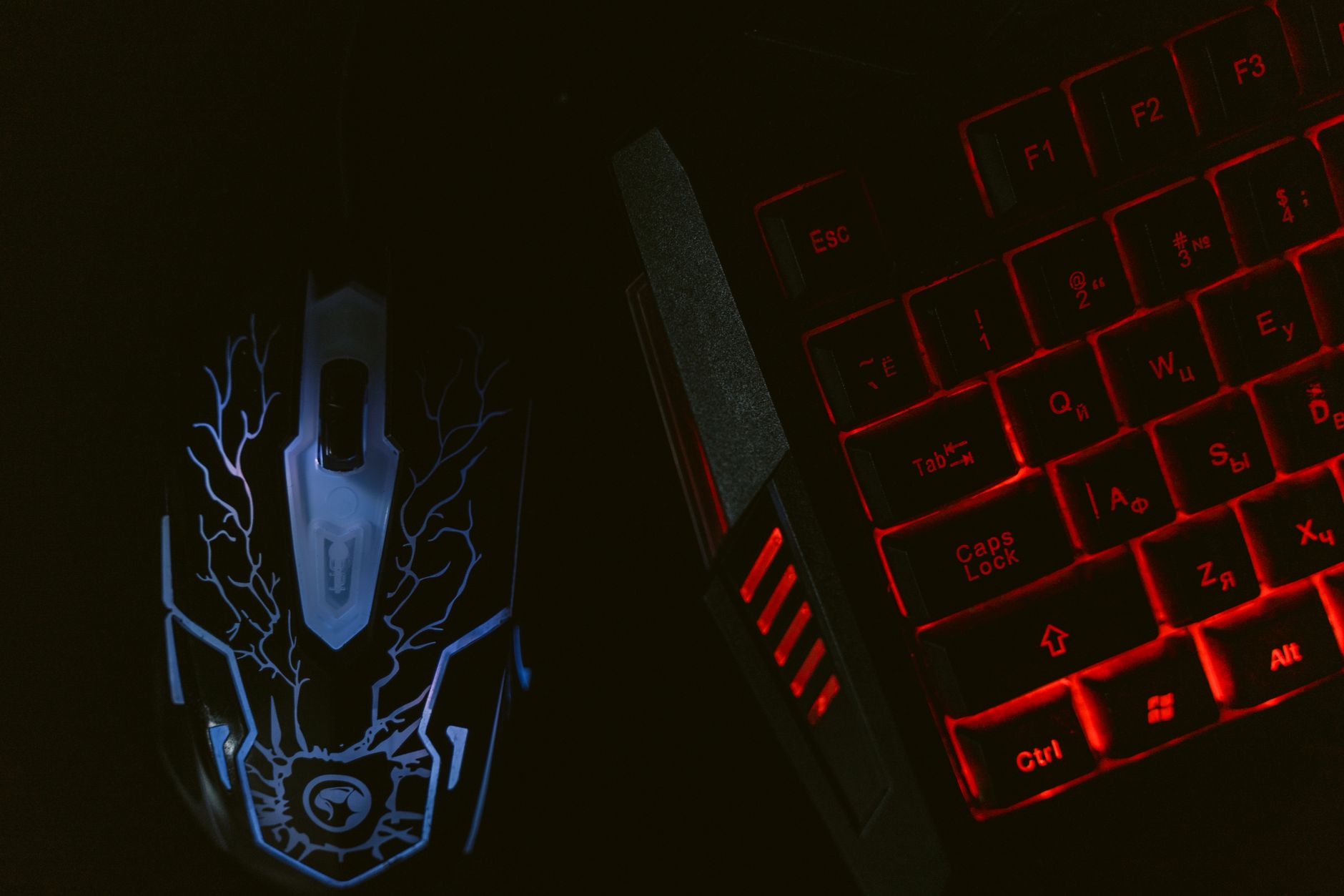 Close-up of a glowing gaming mouse and a backlit keyboard in a dim setting, showcasing a tech-savvy setup.