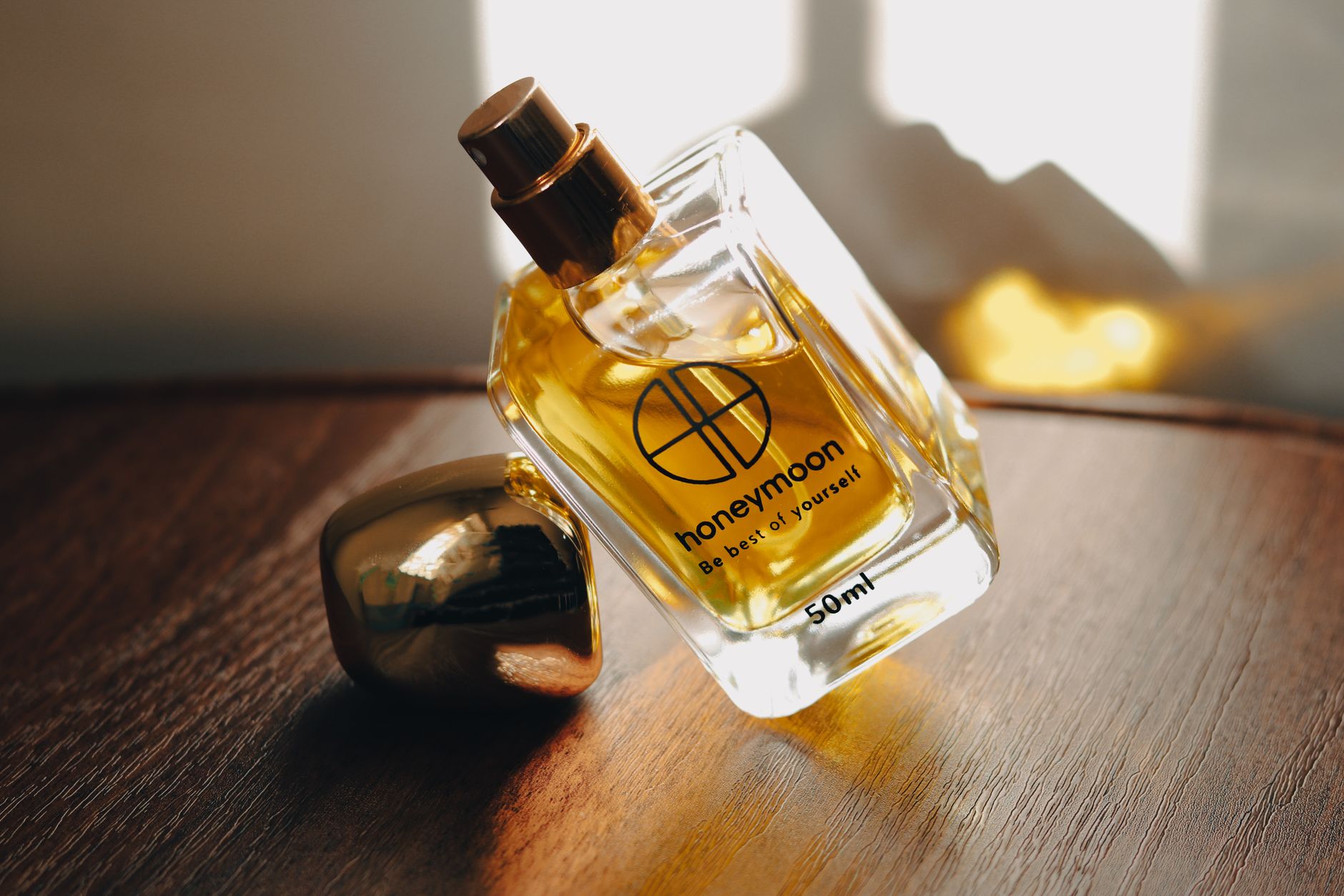 Stylish perfume bottle called 'Honeymoon' rests on a wooden surface, accentuated by sunlight.