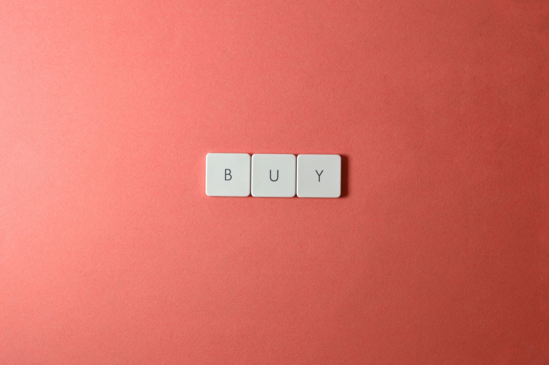 Keyboard keys spelling 'BUY' on a coral background, ideal for e-commerce themes.