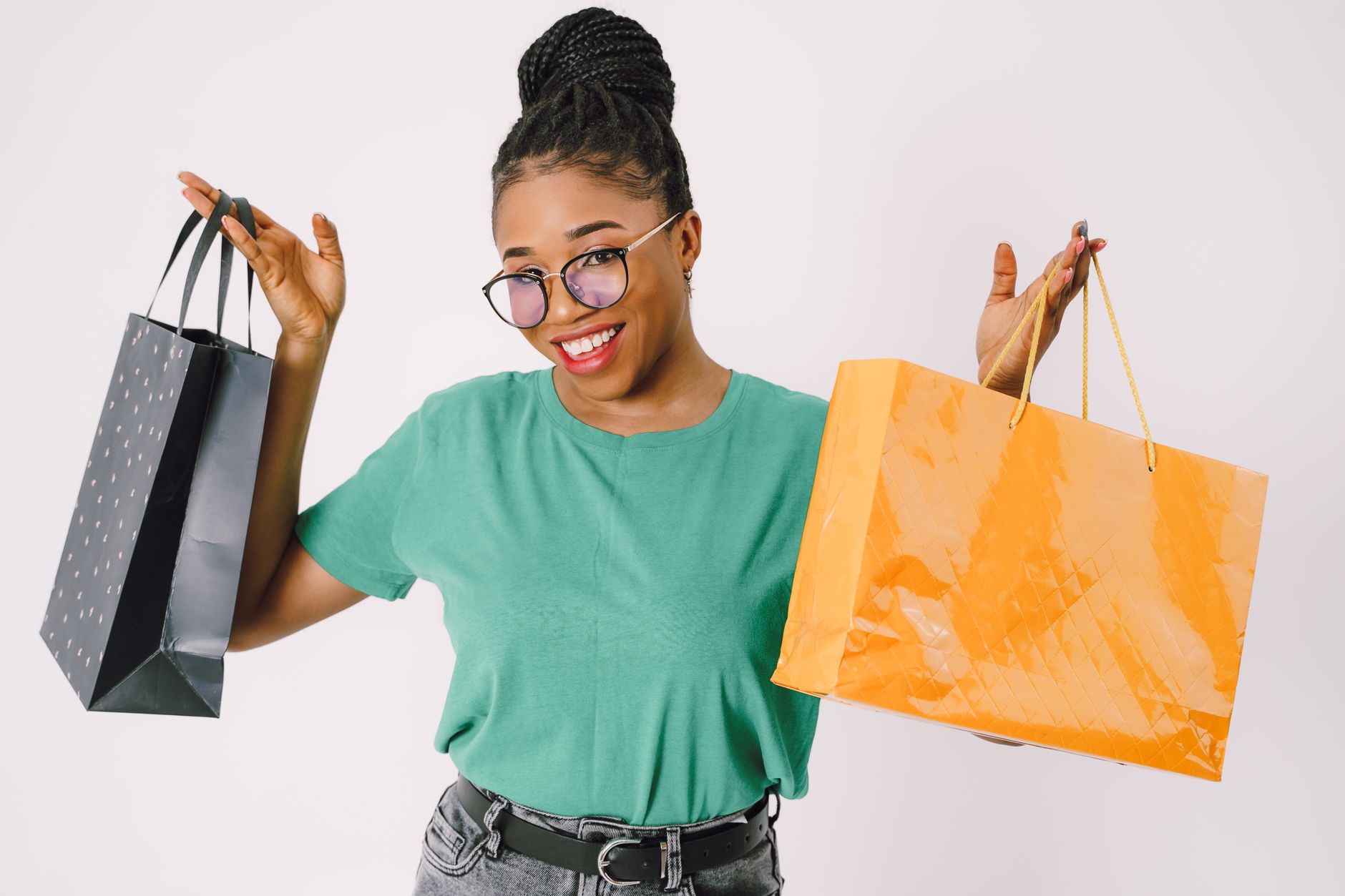 Smiling woman in green t-shirt holding shopping bags, expressing fashion and joy.