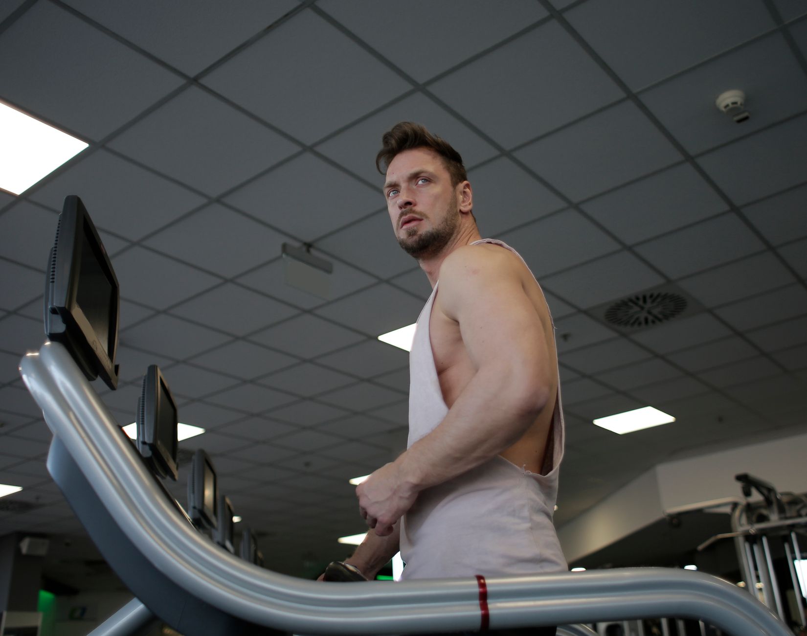 Athletic man working out on a treadmill in a modern gym, showcasing strength and determination.