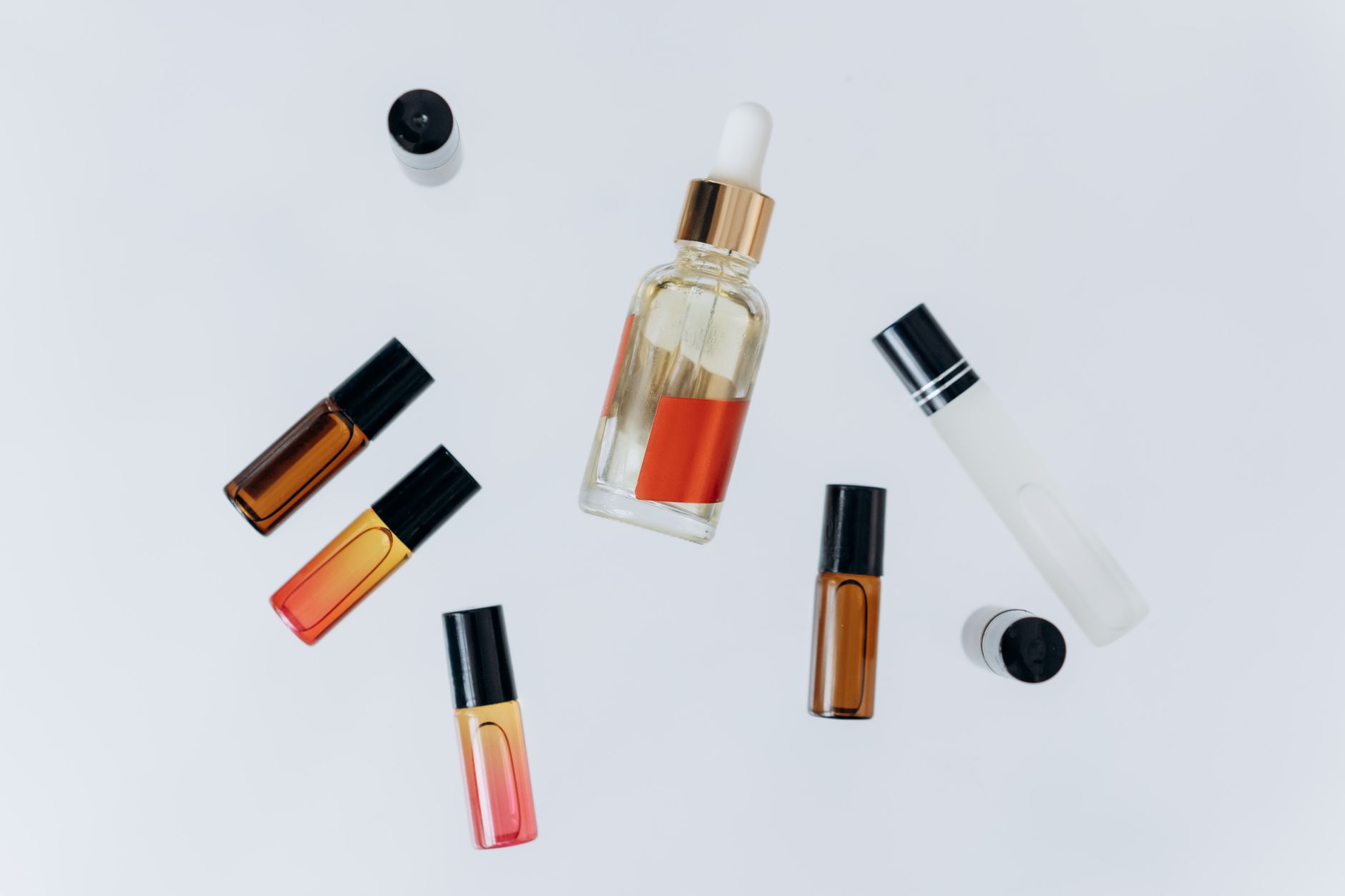 Minimalist flat lay of essential oil bottles with a pipette for beauty and wellness.