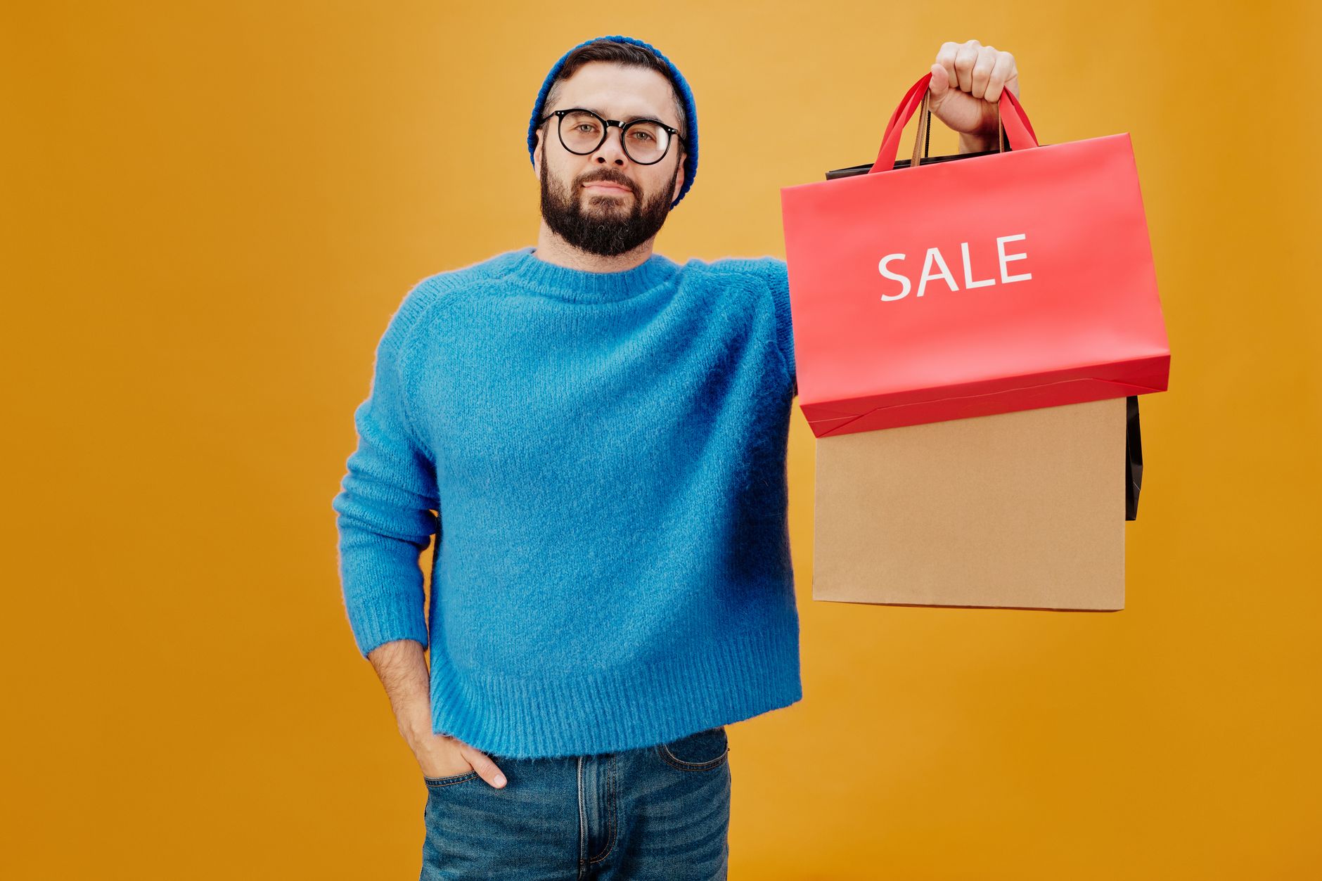 Stylish man holding sale bags against vibrant background, perfect for shopping promotions.