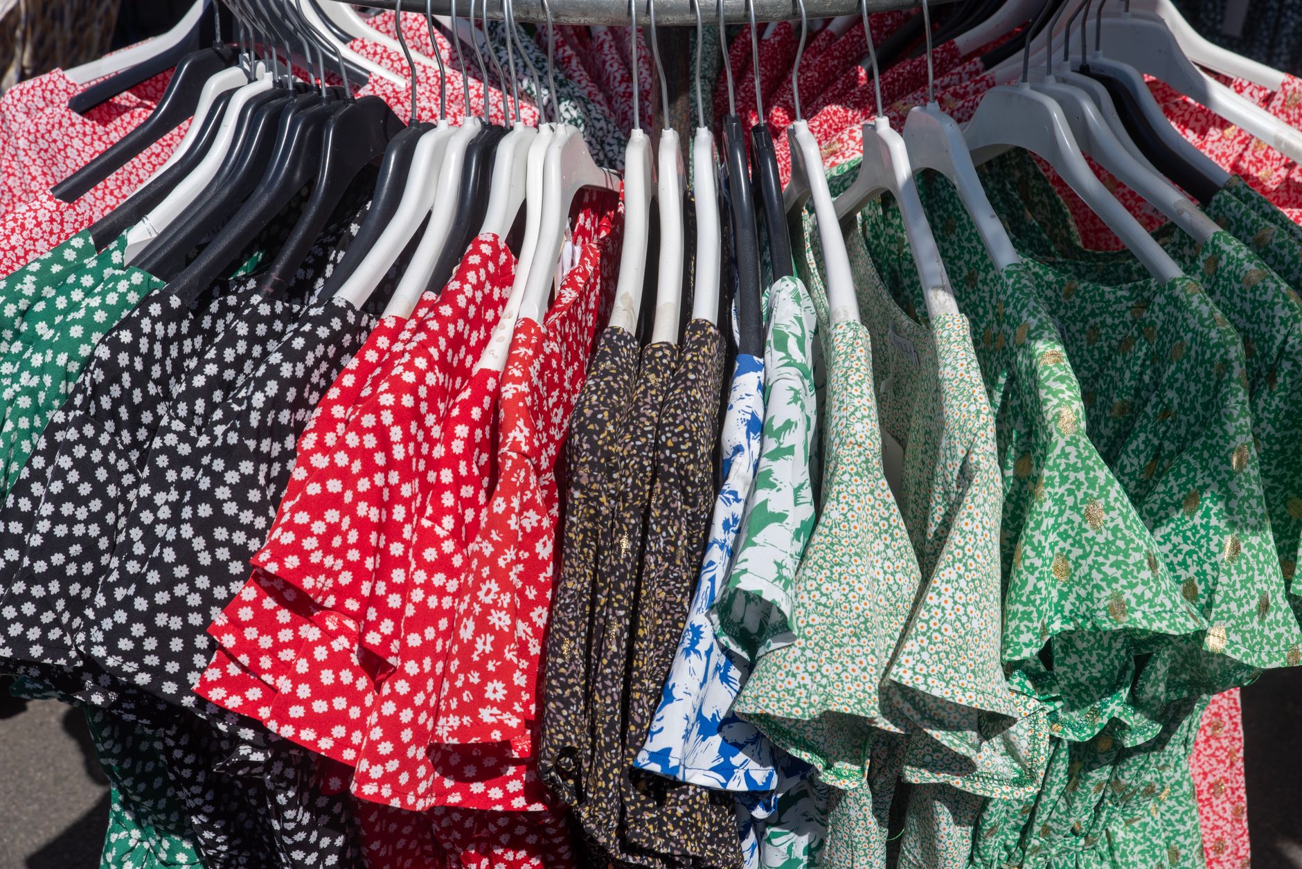 Vibrant collection of floral and patterned dresses hanging on a clothing rack, showcasing diverse styles.