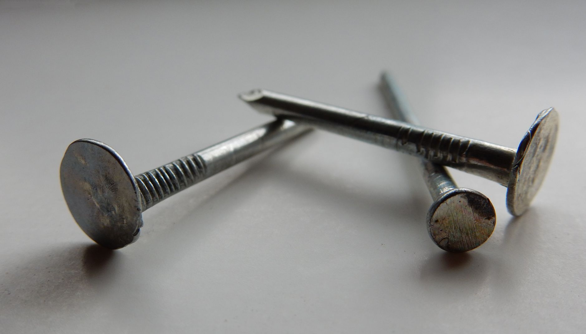 Detailed image of three metallic nails on a white background, highlighting texture and shape.