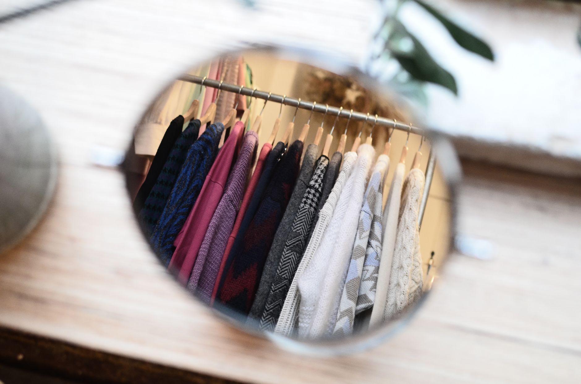 High angle of reflection in mirror with different blouses on hangers hanging on clothes rail