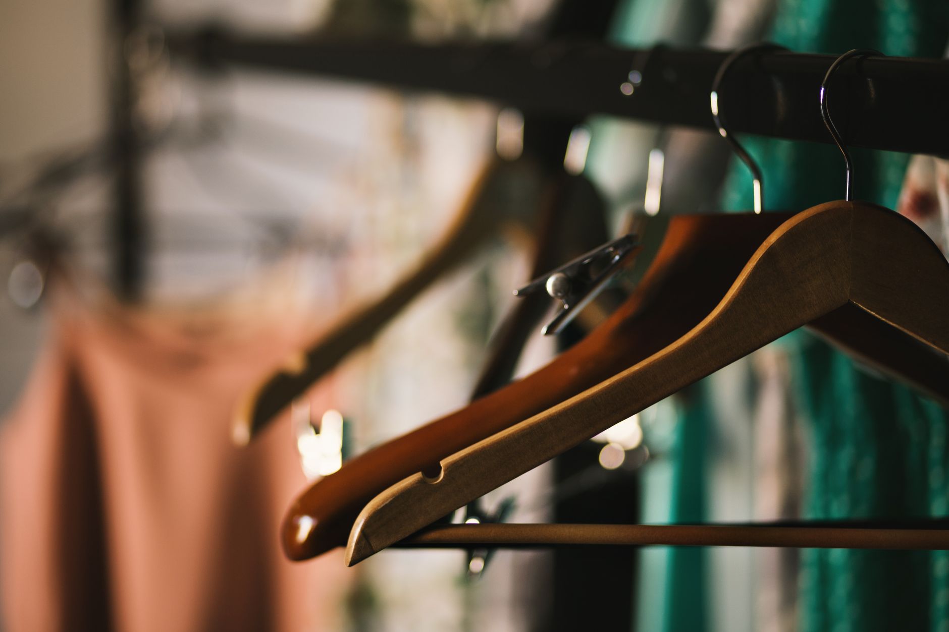 Close-up of wooden hangers on a clothing rack in a blurred indoor setting.