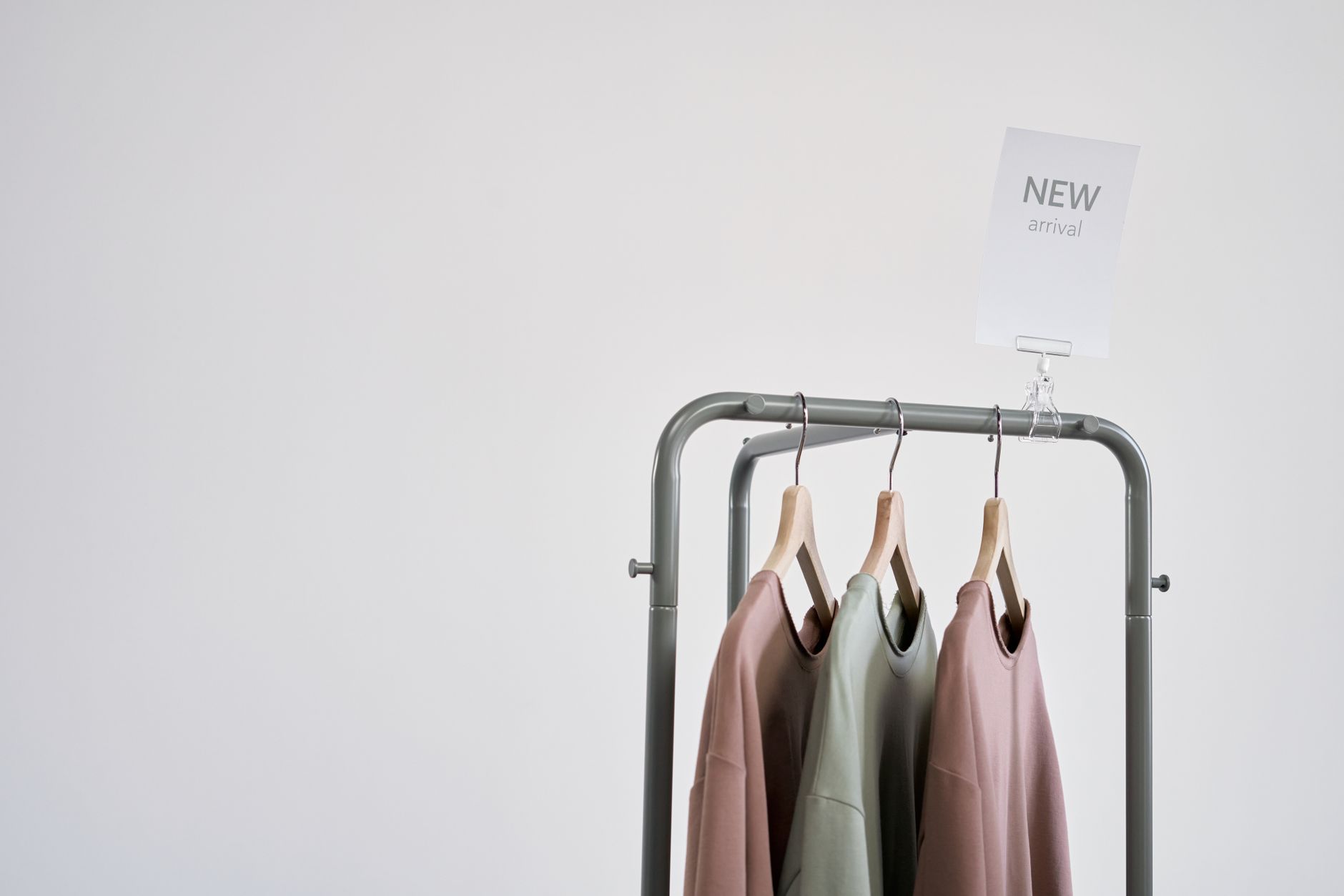 Stylish clothing on a rack with 'New Arrival' sign against a white wall.