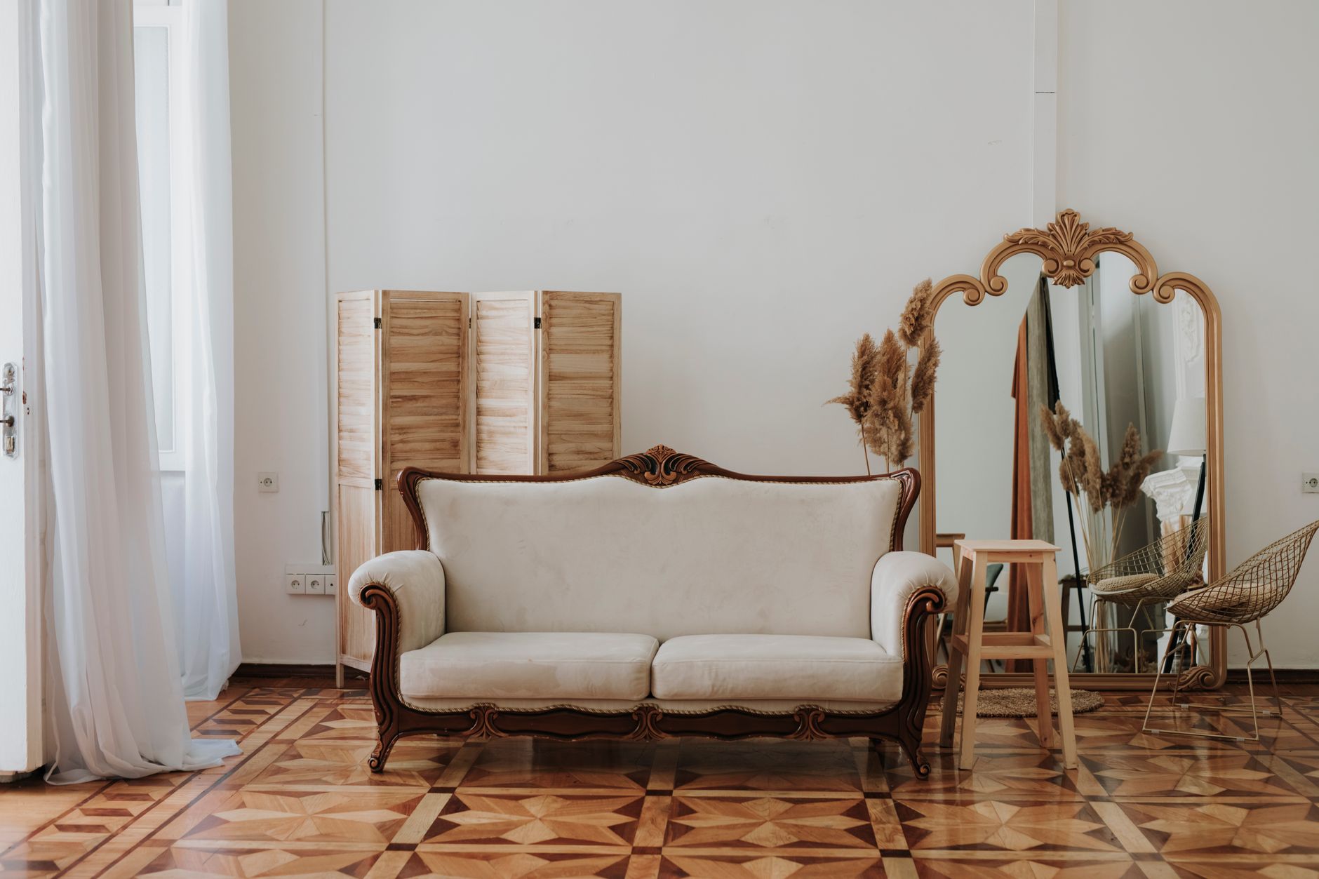 Spacious living room in Baku, featuring a vintage sofa, elegant mirror, and wooden parquet flooring.