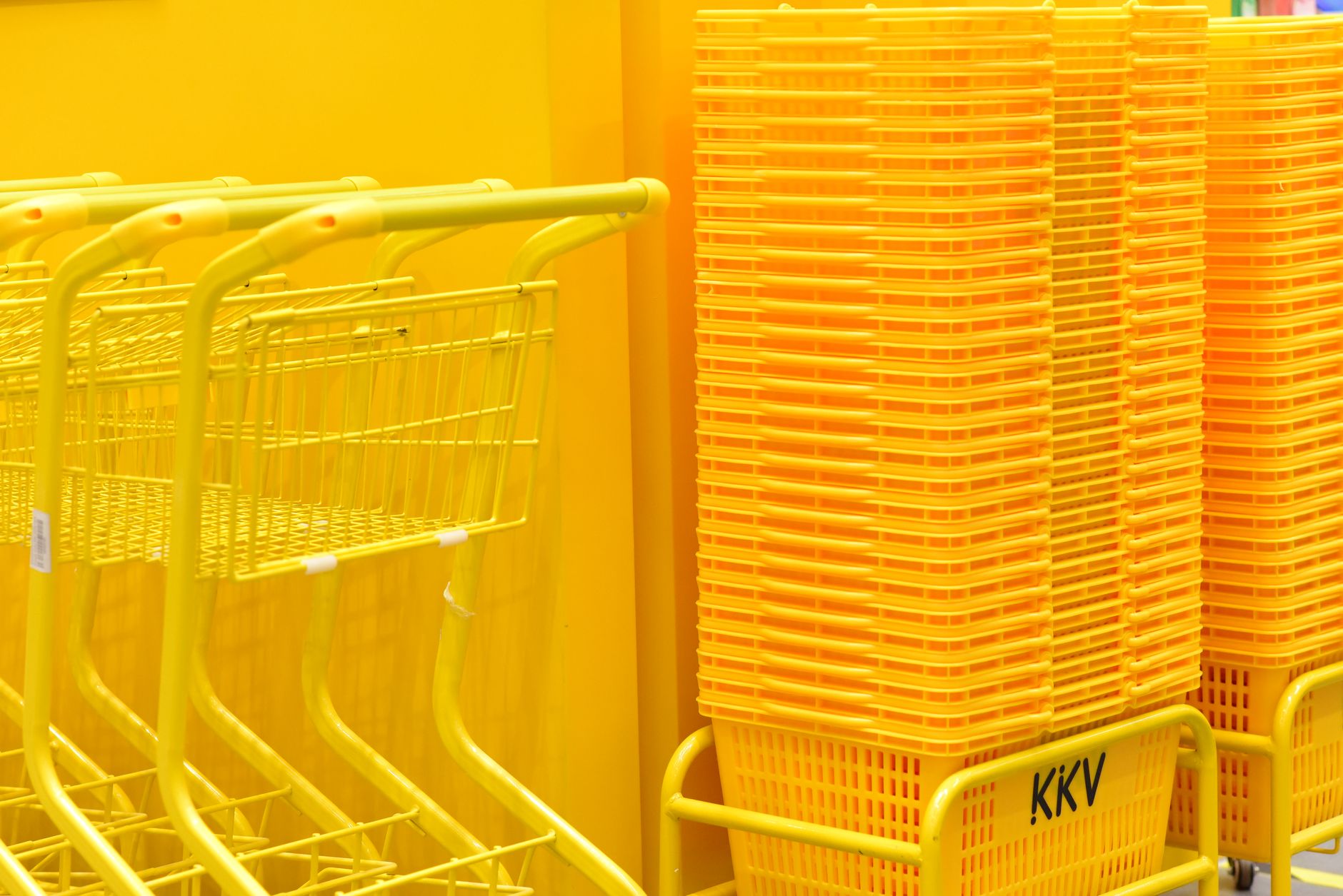 Stack of vibrant yellow shopping carts and baskets in a retail store aisle.