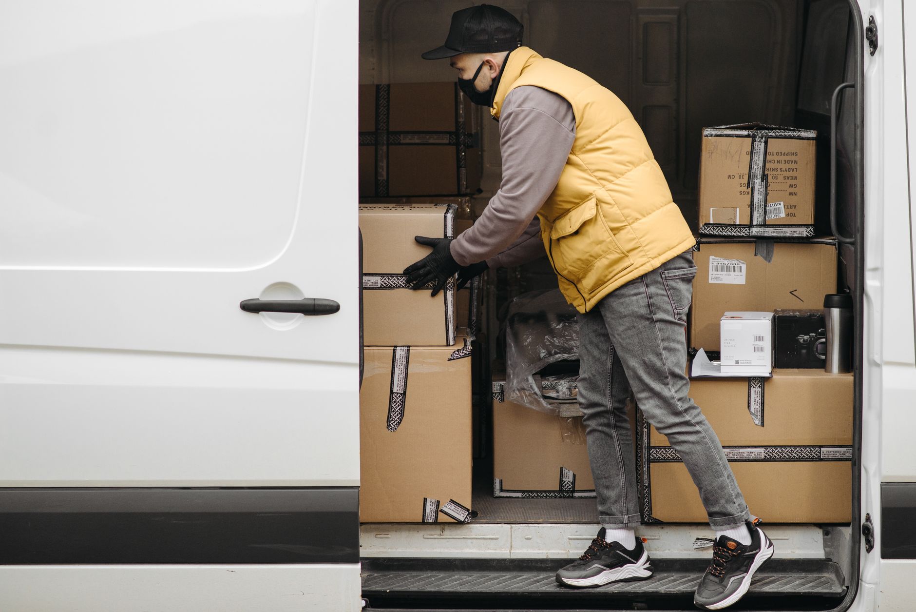 Delivery worker organizing packages in a van, showcasing modern logistics.