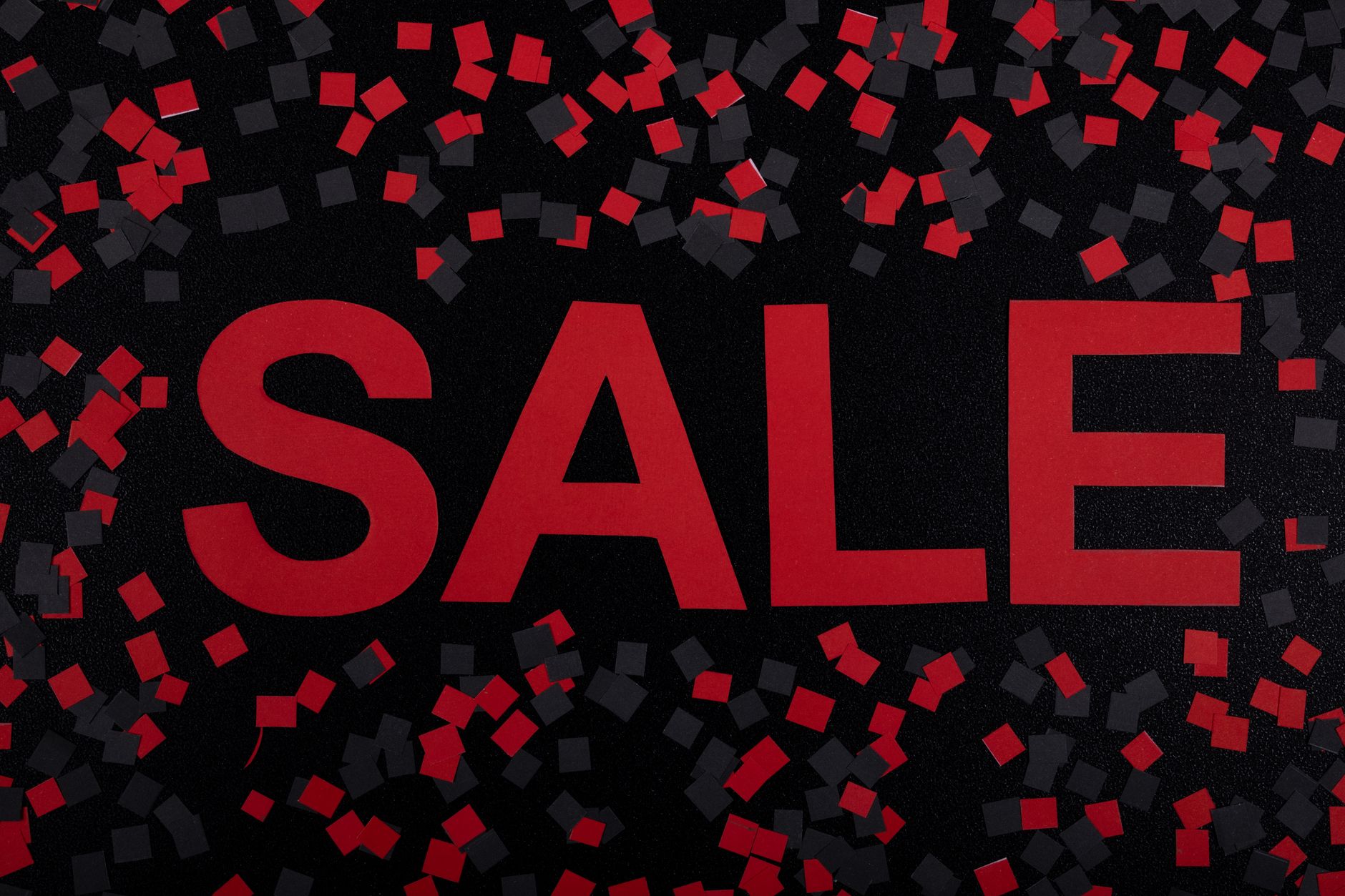 Top view of a red sale sign with black and red confetti, perfect for promotions.