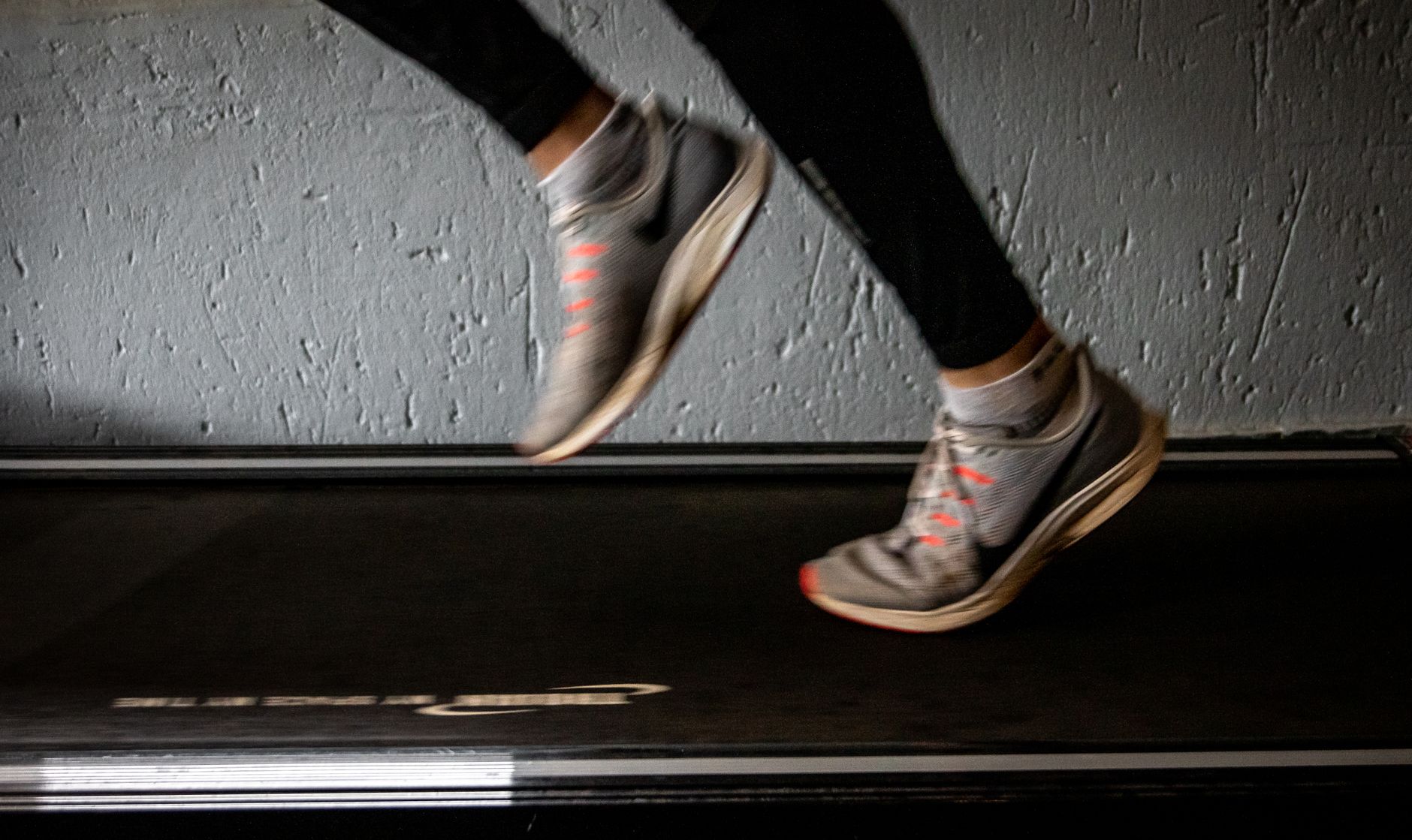 Blurred image of a person running on a treadmill, emphasizing movement and speed.
