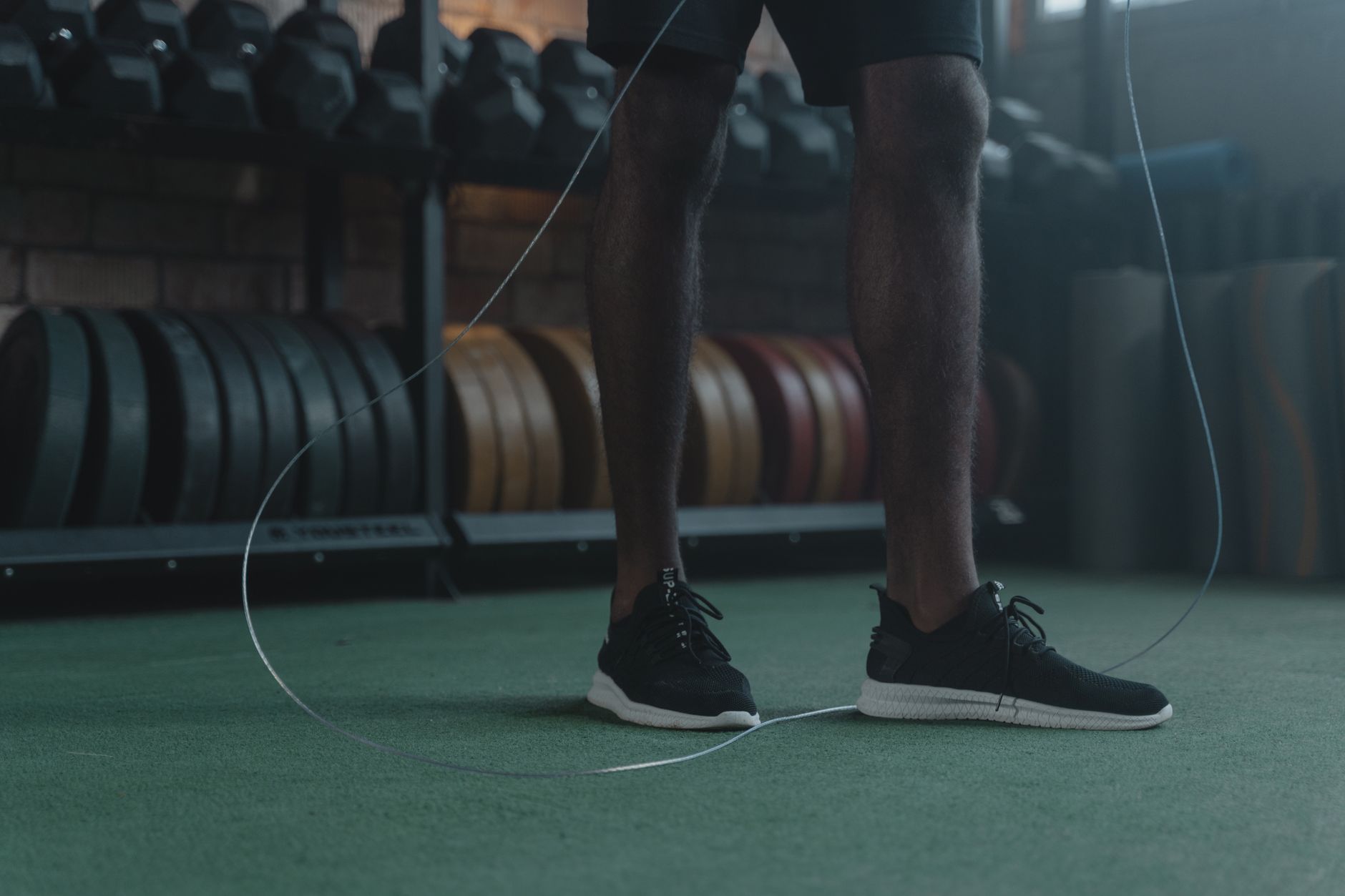 Focused athlete performing jump rope exercises in a stylish indoor gym setting.