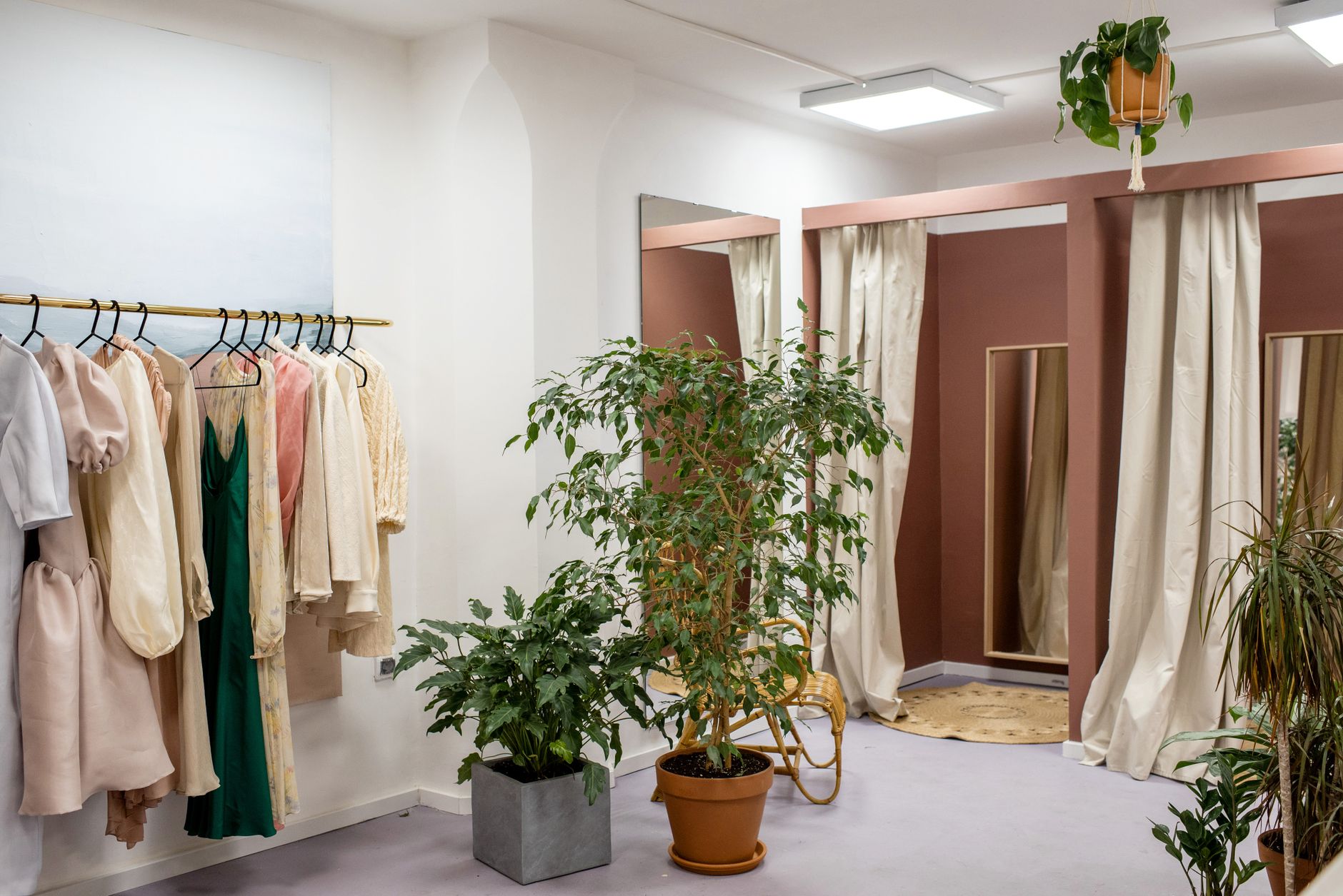 Stylish boutique interior showcasing elegant garments on rack with green plants.