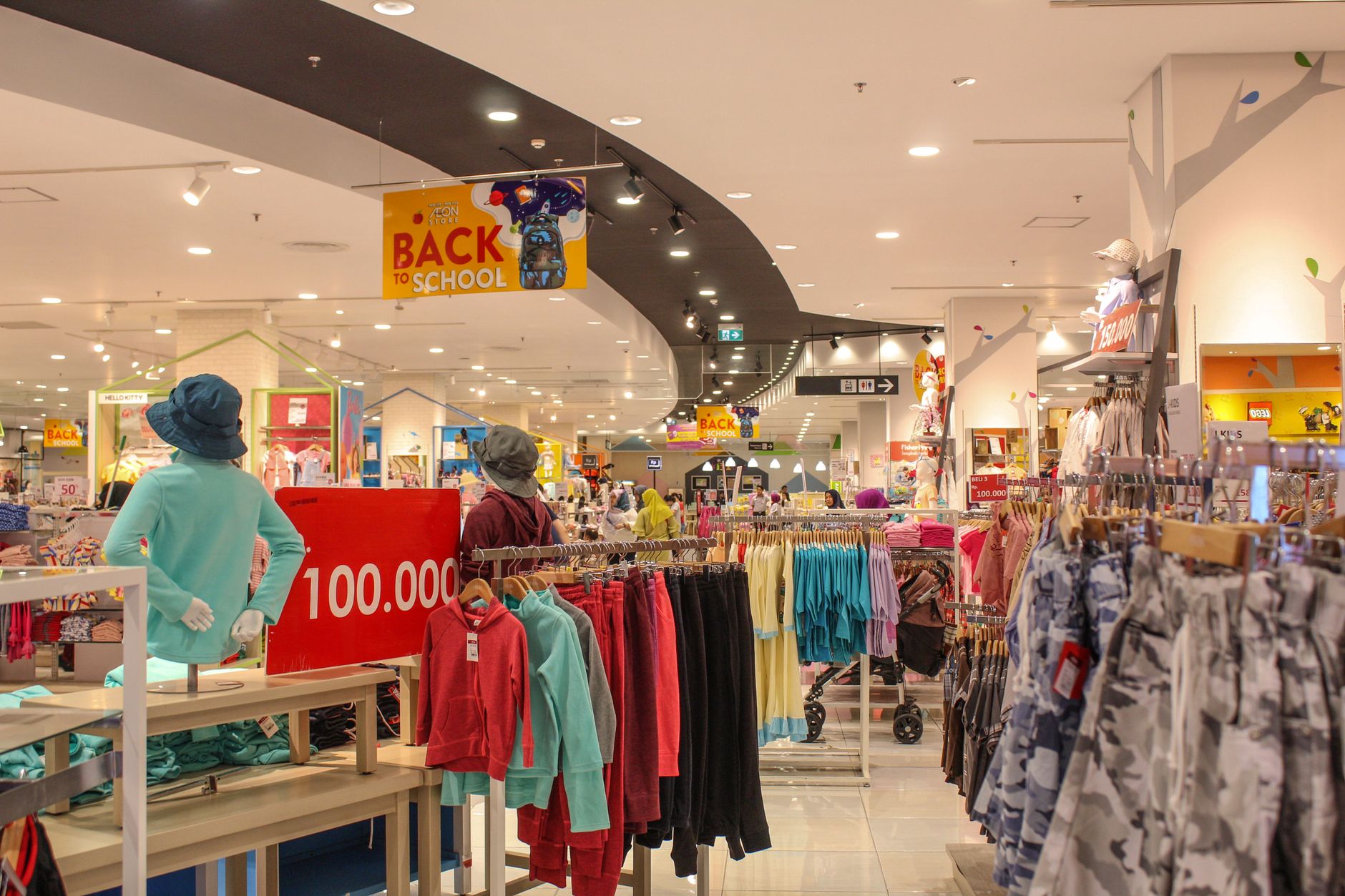 Lively department store aisle displaying colorful back to school clothes under bright lighting.