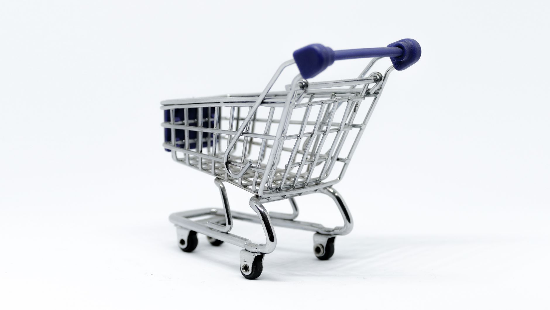 A close-up view of a miniature shopping cart on a white background.